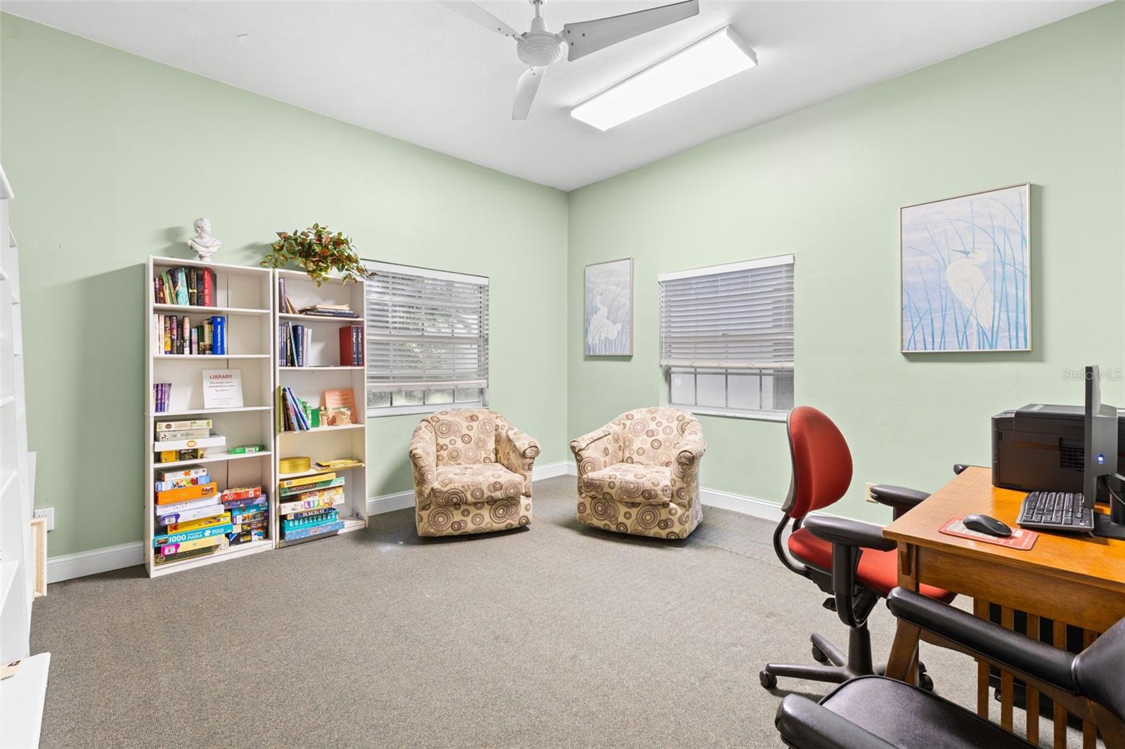 A quieter corner of the clubhouse is set up as a library and computer room, with books, games, comfortable seating and a workstation available for community use.