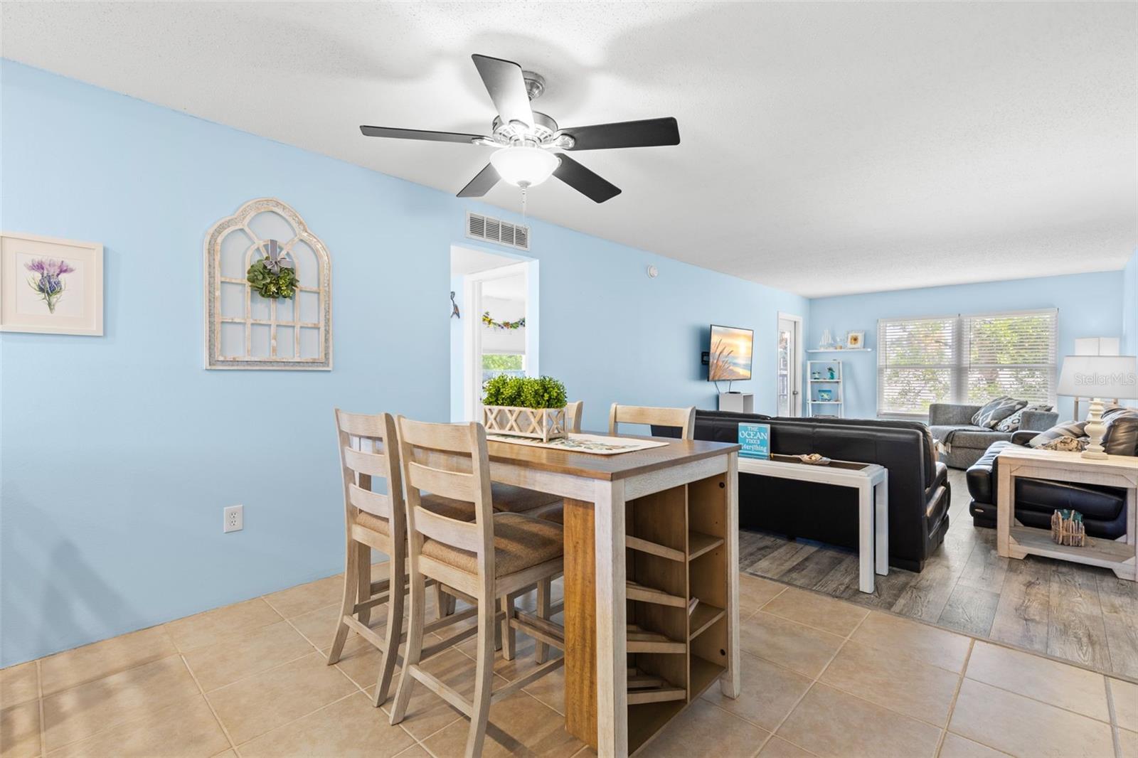 A second view of the dining area shows how naturally it opens into the living room, with tile flooring transitioning to luxury vinyl and a wide bank of windows bringing light into the far end of the space.