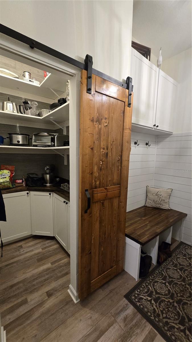 Large Laundry Room with a walk in storage room with additional cabinets.  Plus a sitting bench and wash sink.