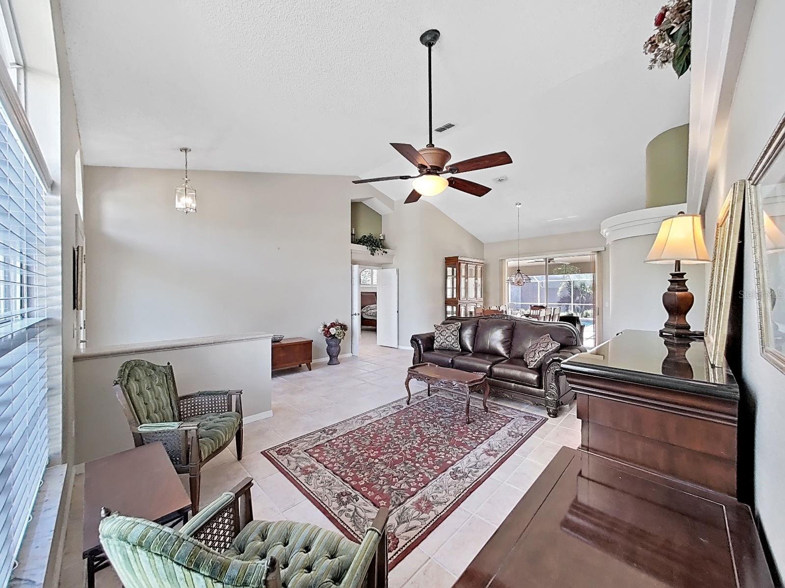 living rm,  note double-door entry to primary bedroom suite, dining room with sliders to pool area and great view of the back yard