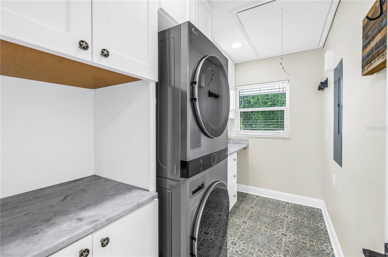 Oversized laundry room with Shaker cabinetry, quartz countertops (all match kitchen), utility sink, storage and FULL size stackable LG ThinQ high efficiency washer and dryer.