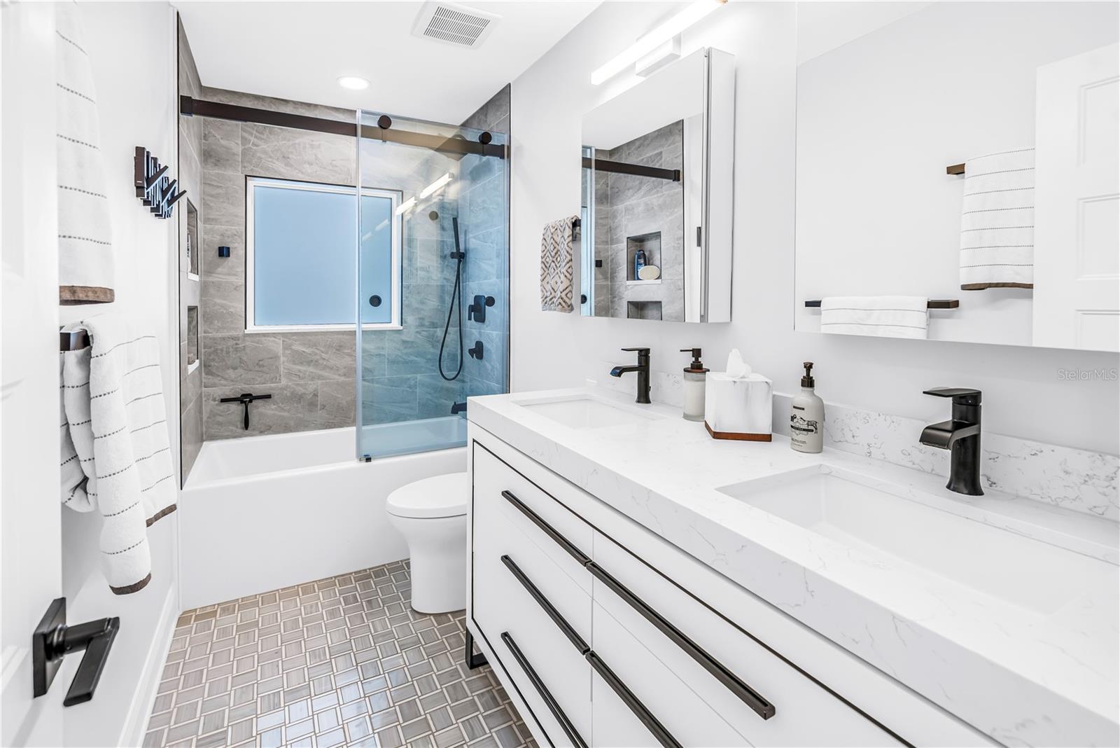 2nd bath with deep soaking tub, custom dual vanity with European style drawers, stone countertops, 2  Robern medicine cabinets, frosted glass window for natural light and comfort height European style flush toilet.