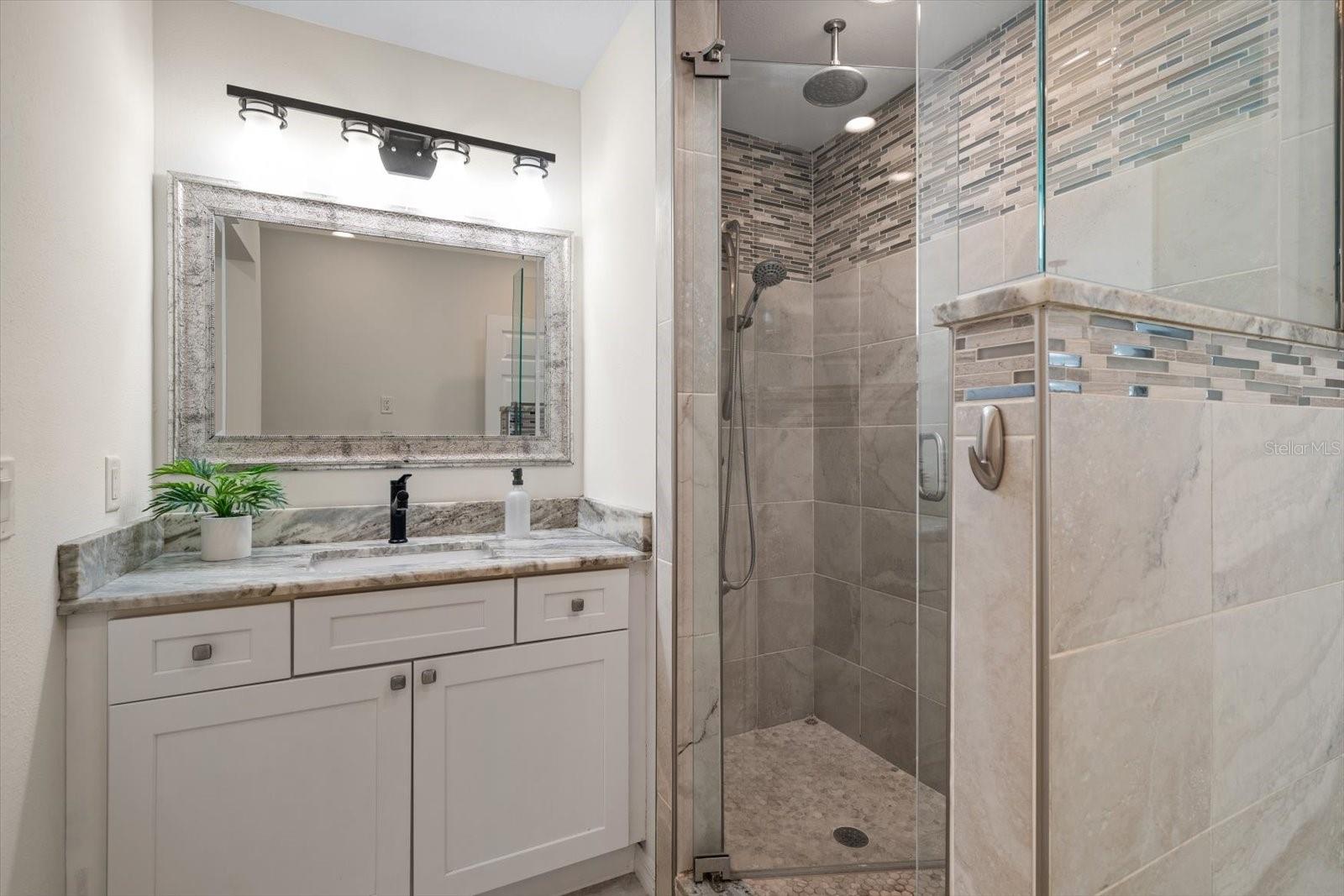Gorgeous bathroom with walk-in tiled shower and granite countertops.