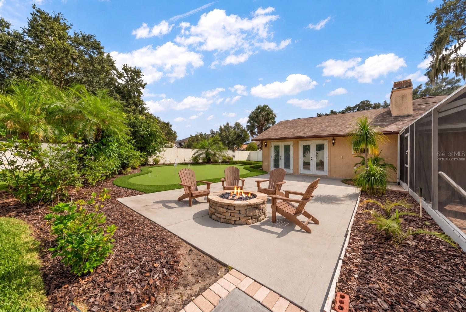 Looking out from patio with virtually staged fire-pit and putting green.
