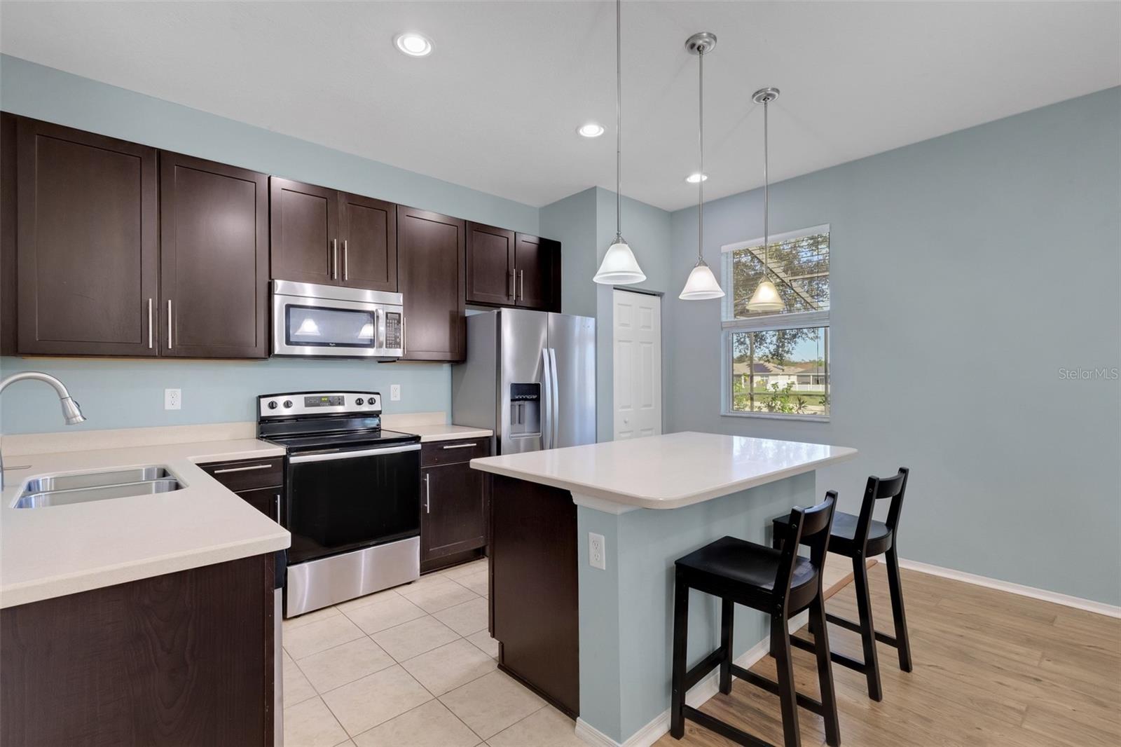 Kitchen featuring Corian Countertops, Breakfast Bar, Soft Close Cabinetry, Stainless Steel Appliances, Closet Pantry