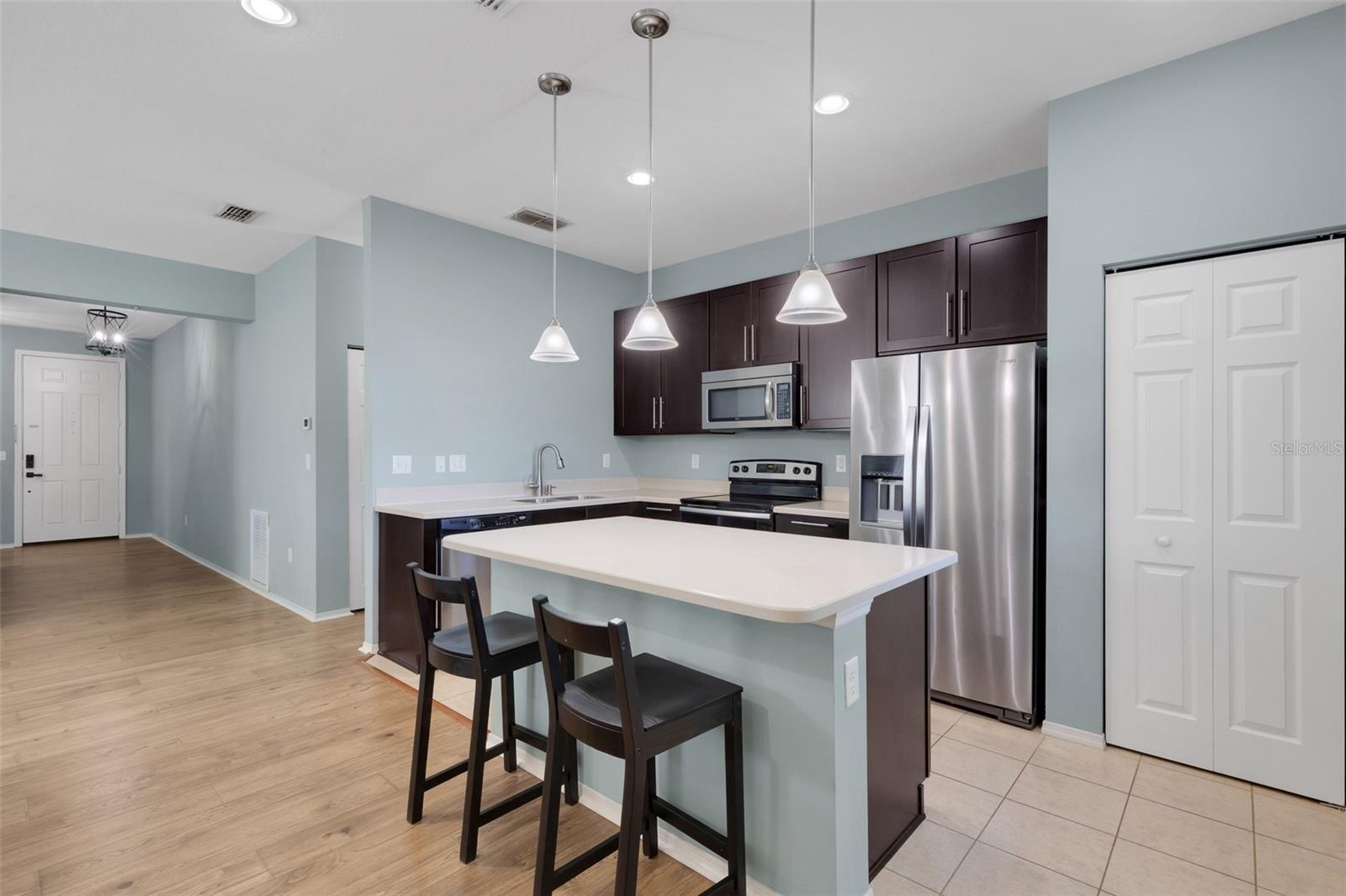 Kitchen featuring Corian Countertops, Breakfast Bar, Soft Close Cabinetry, Stainless Steel Appliances, Closet Pantry