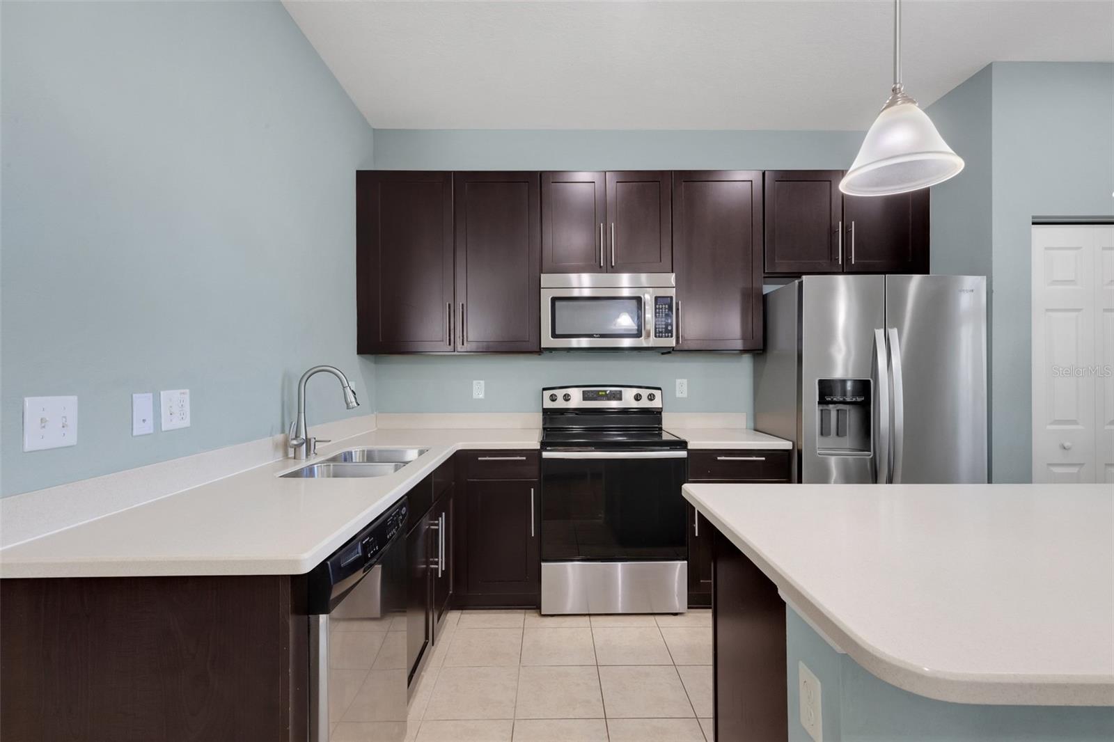 Kitchen featuring Corian Countertops, Breakfast Bar, Soft Close Cabinetry, Stainless Steel Appliances, Closet Pantry
