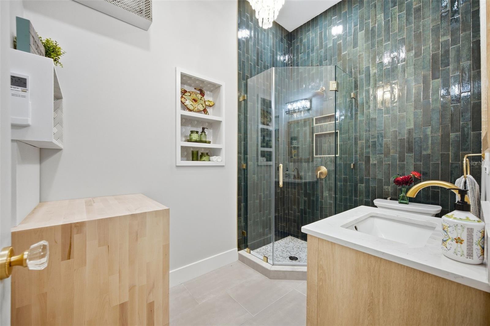 Striking primary en suite with dramatic floor-to-ceiling tile, frameless glass shower