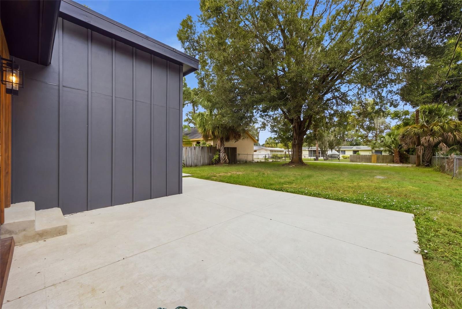 Expansive concrete patio provides versatile space for outdoor dining, entertaining, grilling or relaxing