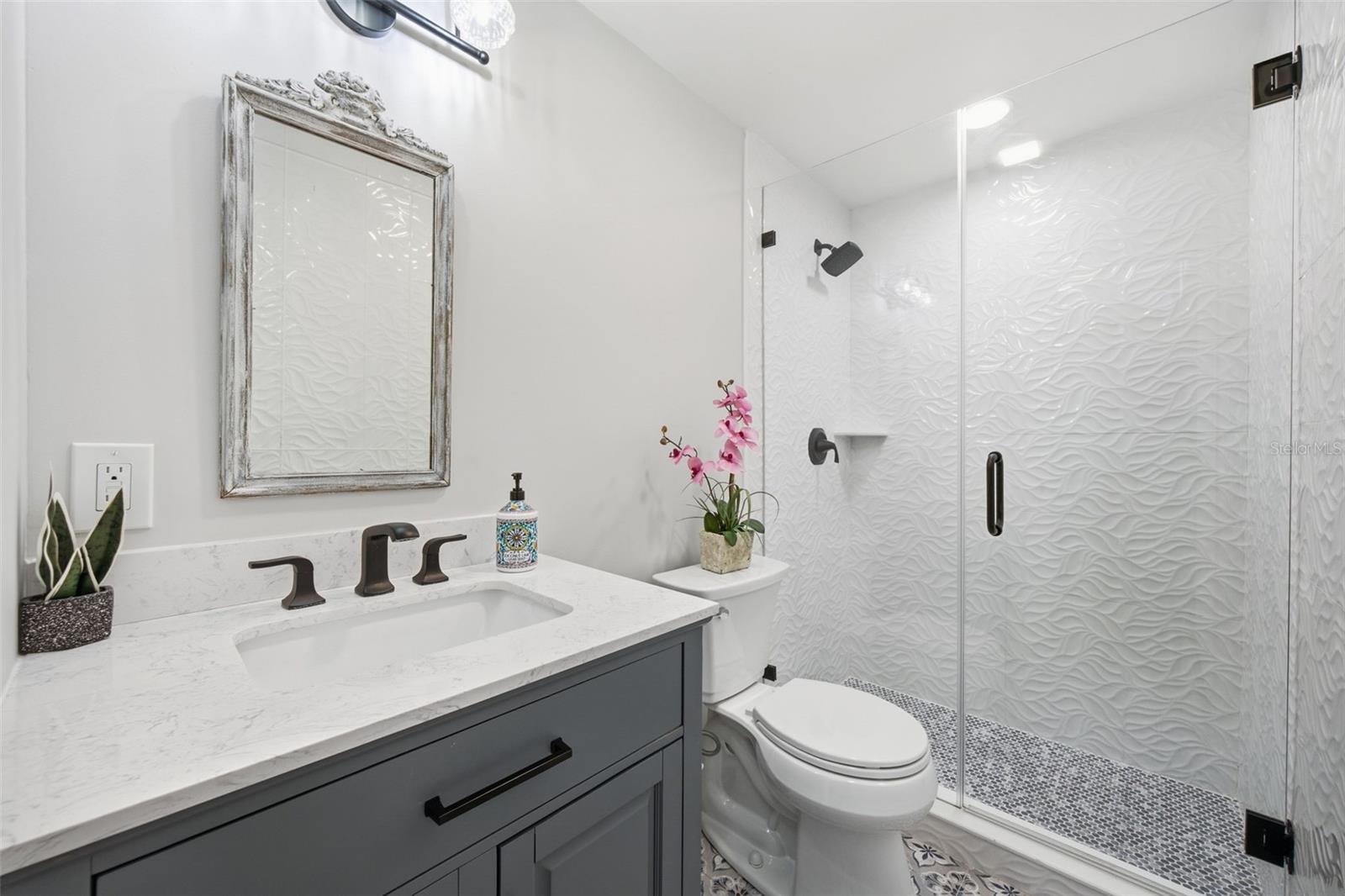 Beautifully updated main bath featuring sculptural 3D wave tile, frameless glass shower.