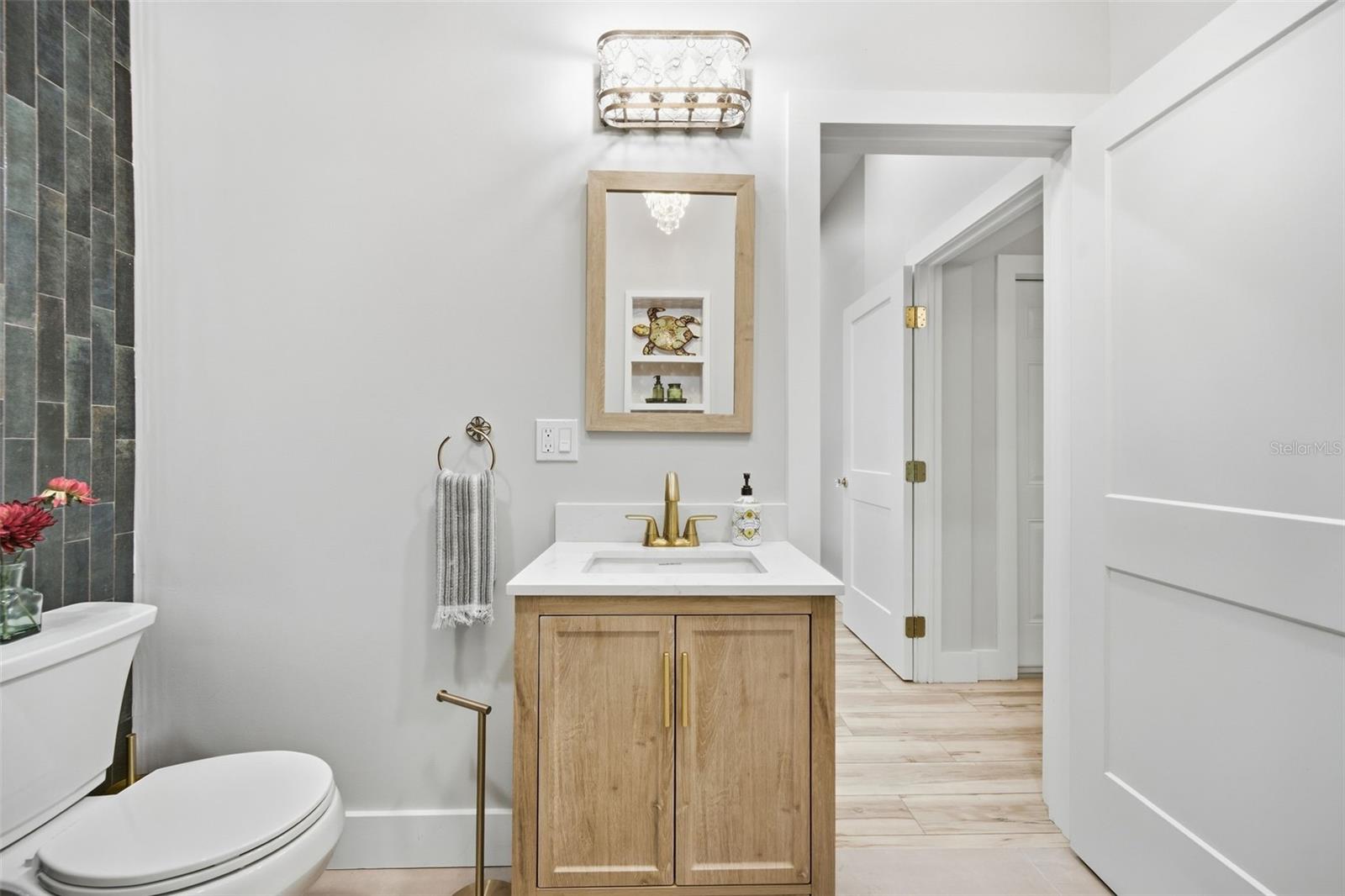 Light-wood vanity Brass fixtures and statement crystal lighting