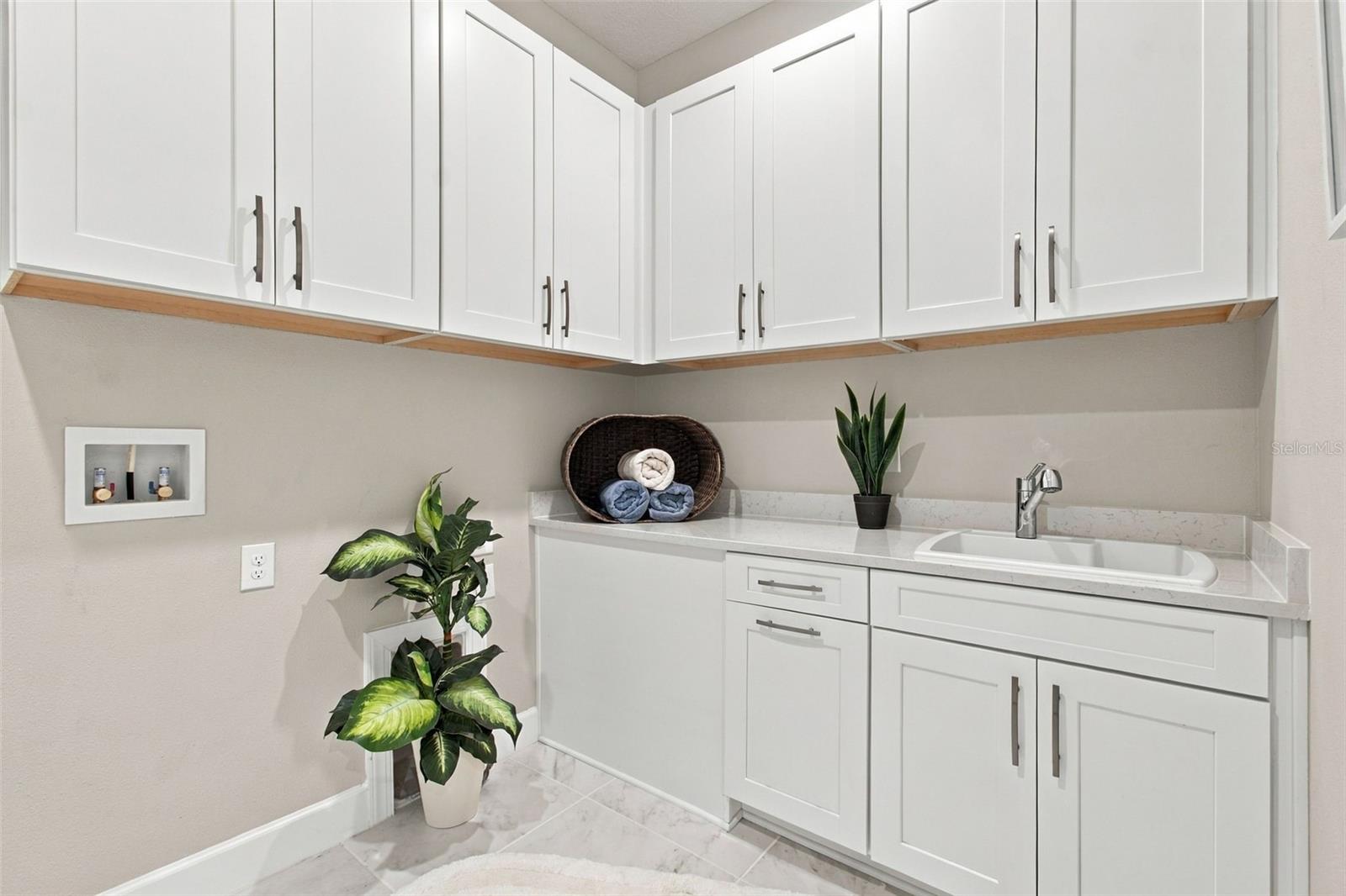 Very large laundry room with upper and lower cabinets and a utility sink