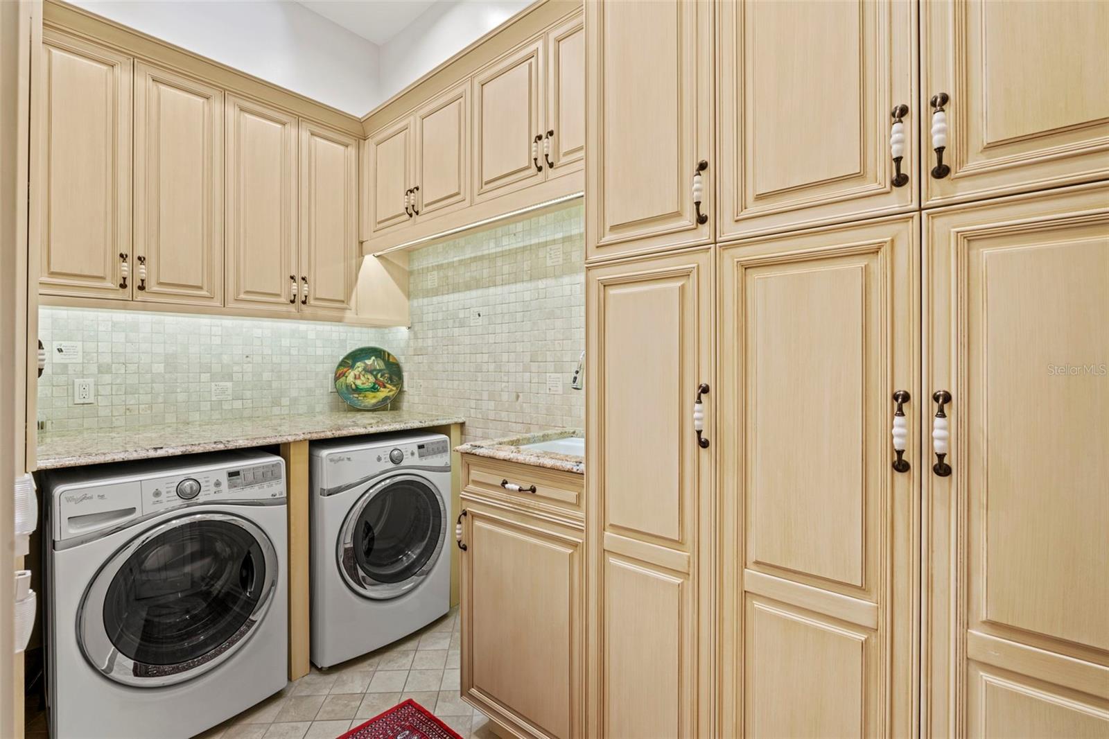 Laundry Room with sink and plenty of custom storage cabinets for cleaning supplies and paper goods.