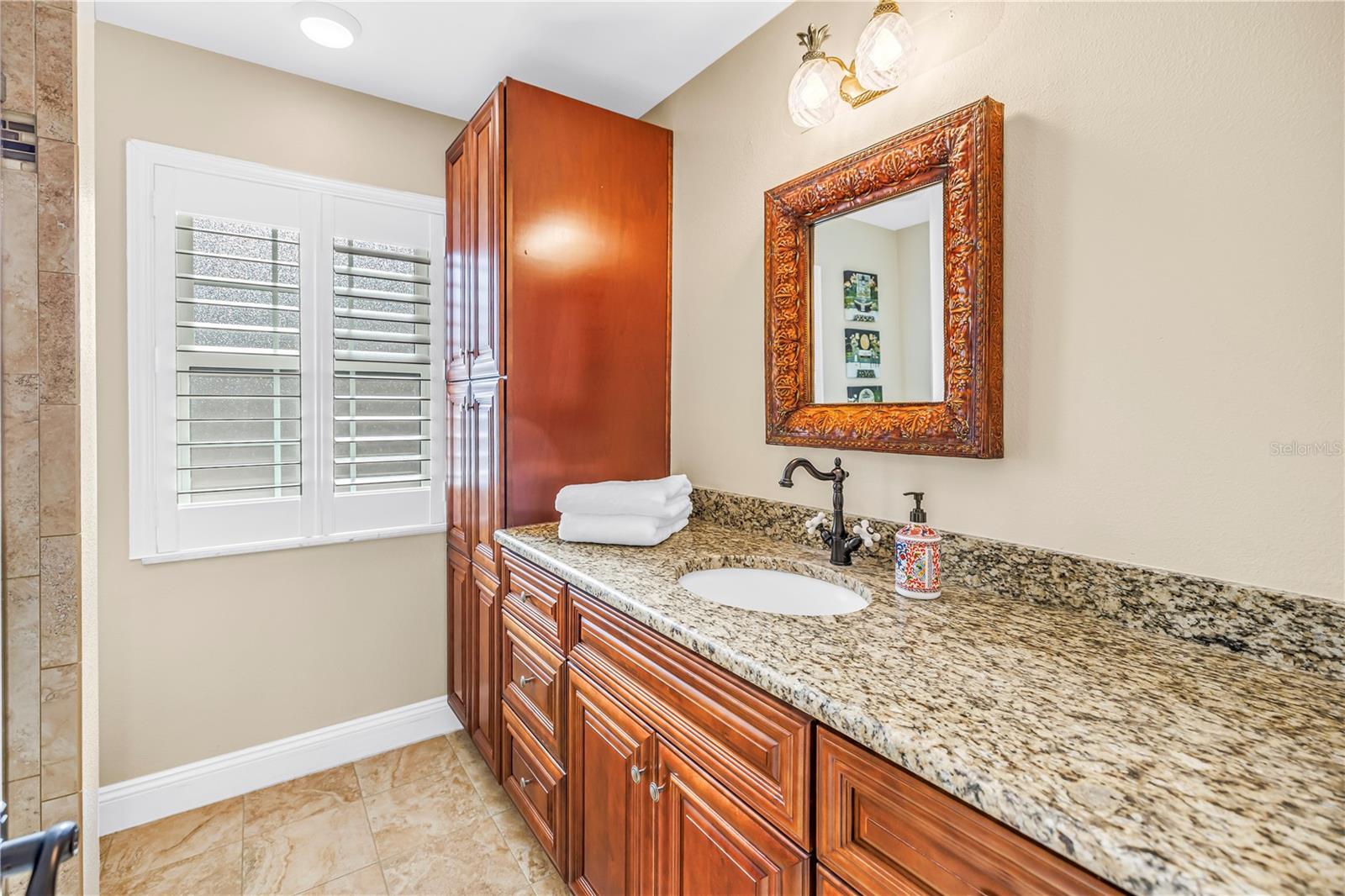 Primary bathroom featuring a second granite vanity, ample storage cabinetry, and custom-built fixtures.