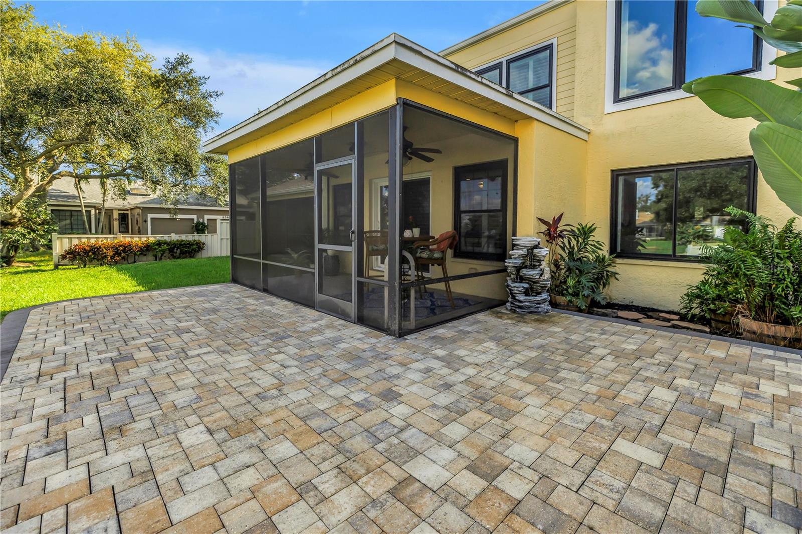 This screened, covered patio features a raised paver deck, providing an ideal space for an outdoor kitchen or grill.  Adirondacks ?!