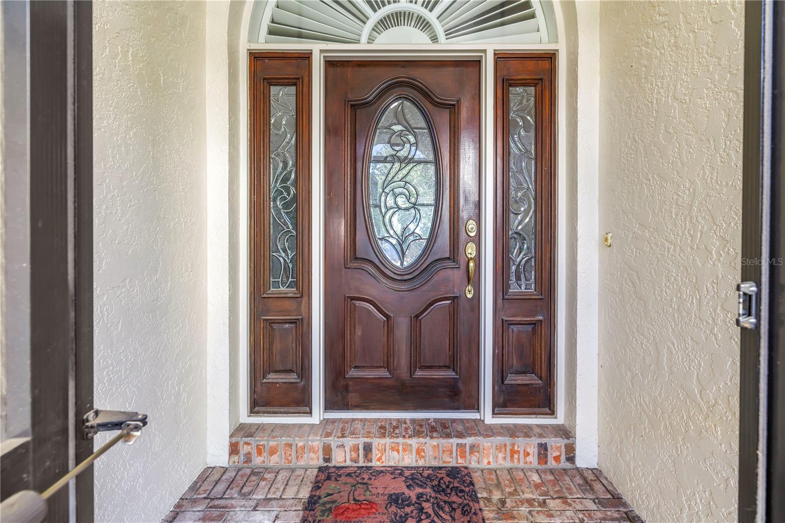 Beautiful front door featuring solid wood construction and elegant leaded glass. This upscale entry is also screened, allowing for refreshing natural breezes.