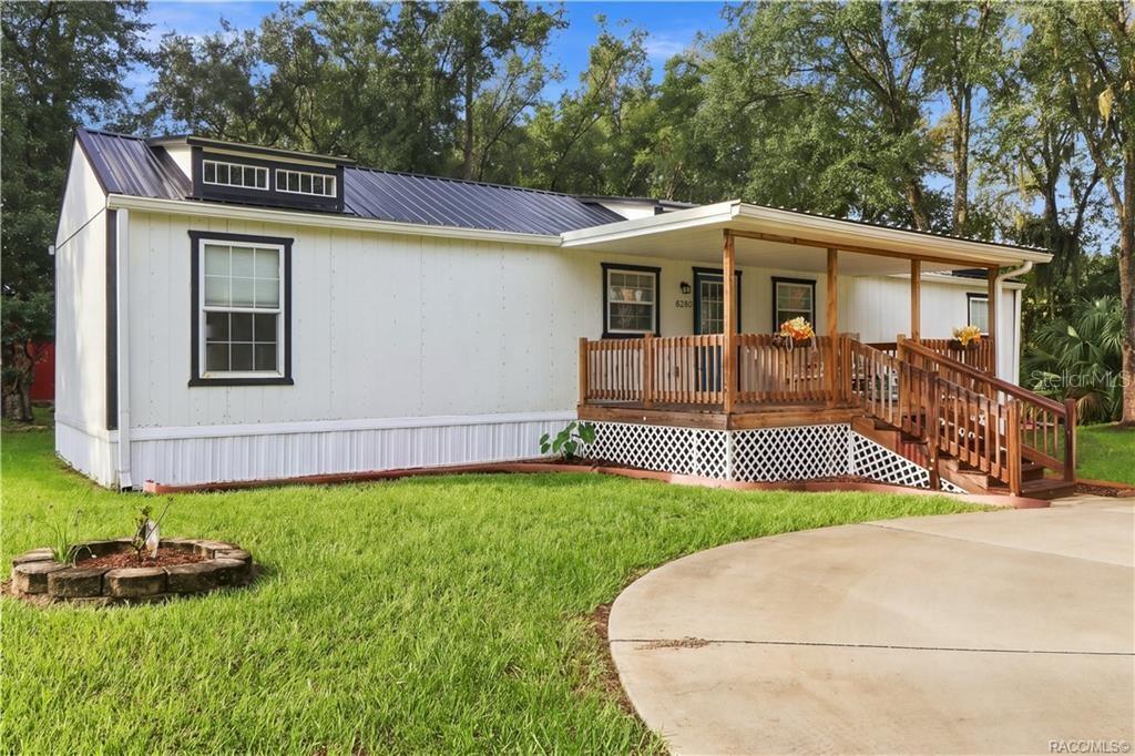 Front Exterior  Attractive white exterior w/contrasting dark trim, METAL ROOF & spacious covered wooden porch, surrounded by a lush green lawn.