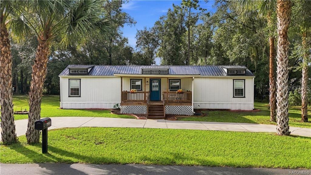 Welcome Home- Front Exterior Attractive home featuring a METAL ROOF, COVERED FRONT PORCH, welcoming blue front door, wooden railings & palm trees framing the property. Welcome Home- Front Exterior Attractive home featuring a METAL ROOF, COVERED FRONT PORCH, welcoming blue front door, wooden railings & palm trees framing the property.