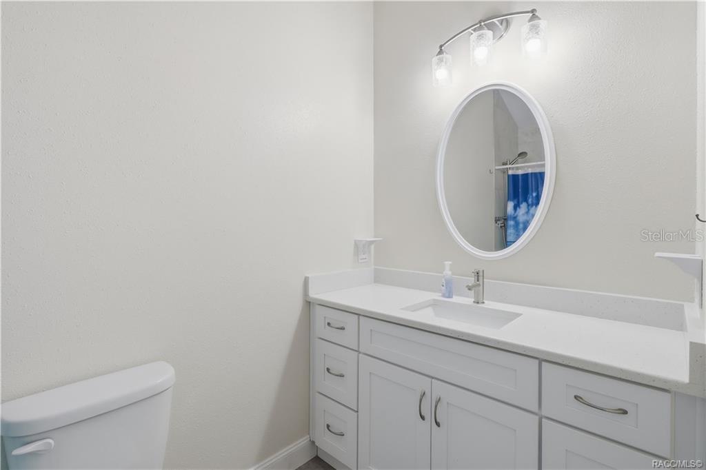 Primary Bathroom  Bright bathroom featuring a white vanity w/solid-surface countertop, undermount sink, oval mirror, attractive lighting & convenient storage cabinetry.