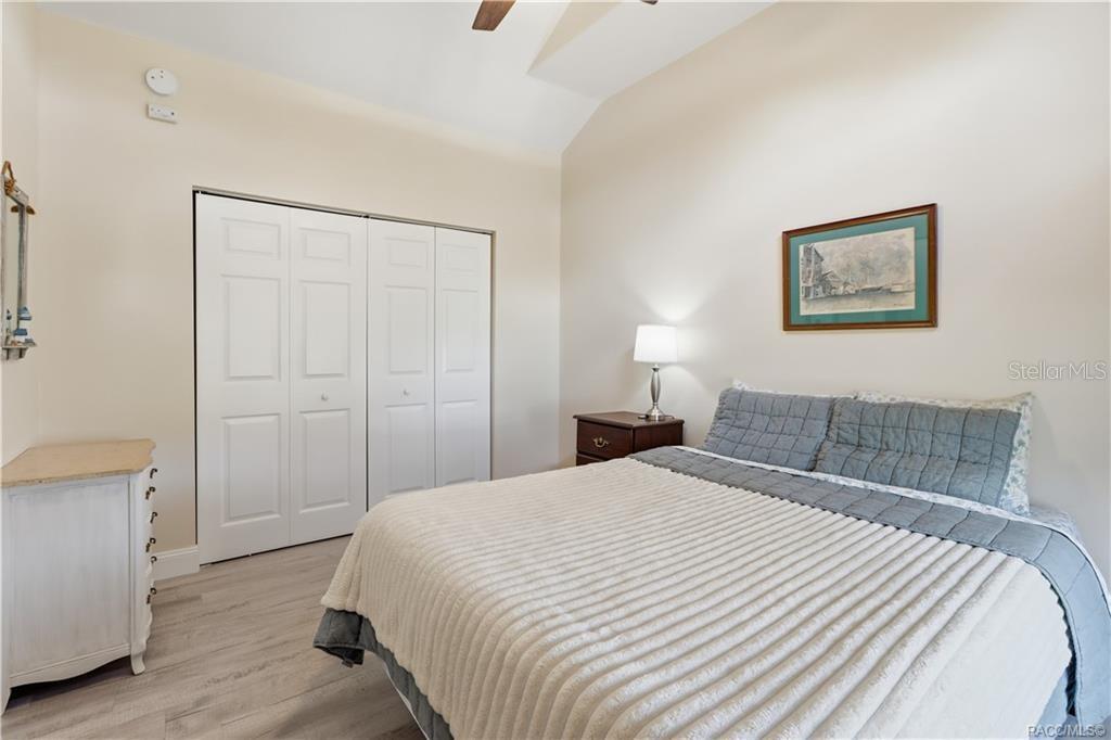 Bedroom  Comfortable bedroom featuring VAULTED CEILINGS, luxury vinyl plank flooring, ceiling fan, spacious double closets & attractive furnishings.