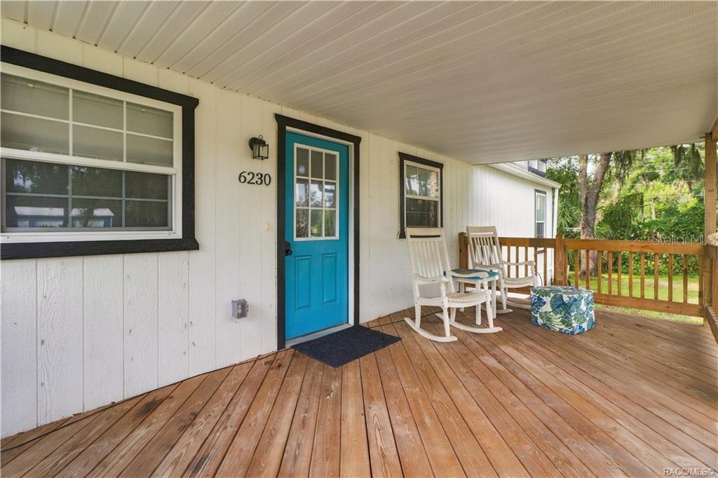 Front Porch Seating  A cozy place to relax, featuring wooden decking, a covered roof & room for rocking chairs to enjoy the Florida breeze.