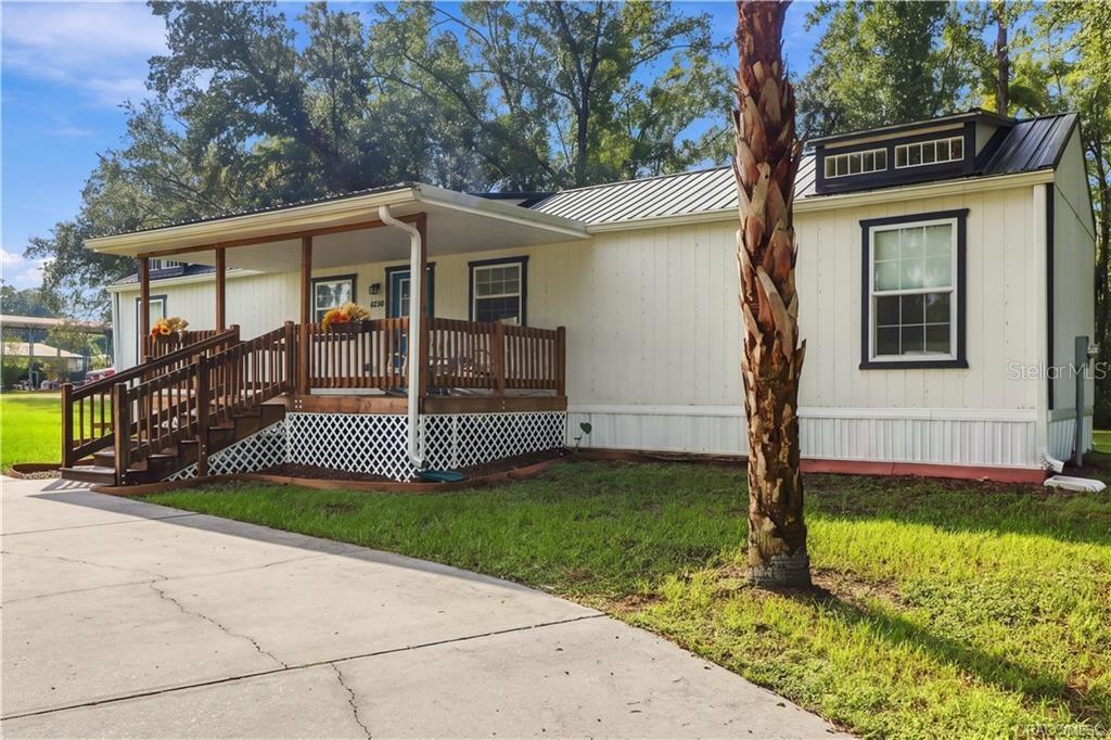 Exterior & Front Porch  Another inviting perspective highlighting the covered wooden porch, contrasting exterior finishes & beautiful palm tree.