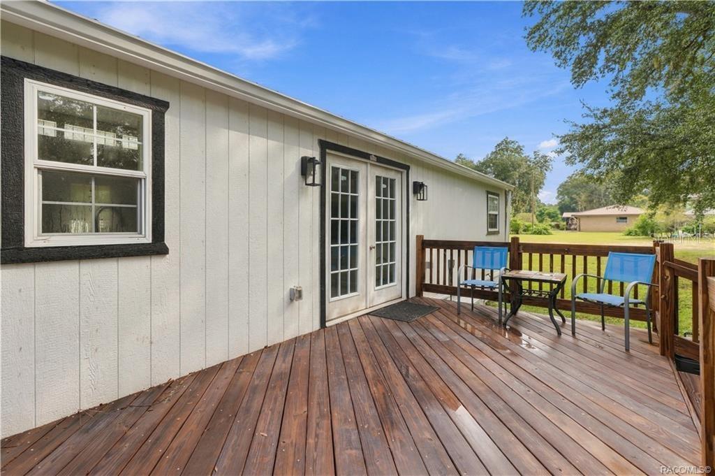 Outdoor Living  Another view of the rear deck showcasing its open layout, wooden railings & easy access to the backyard. A great setting for enjoying Florida's beautiful weather!