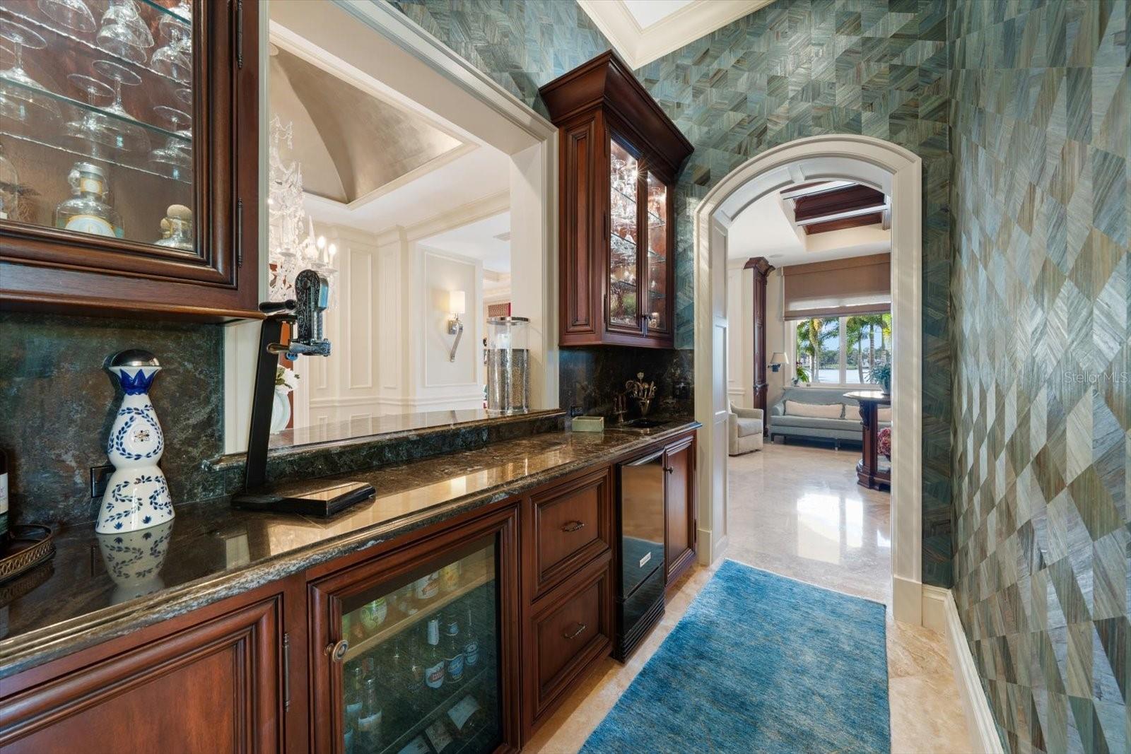 Beautifully appointed wet bar with ice maker, beverage fridge and beautifully displayed stemware