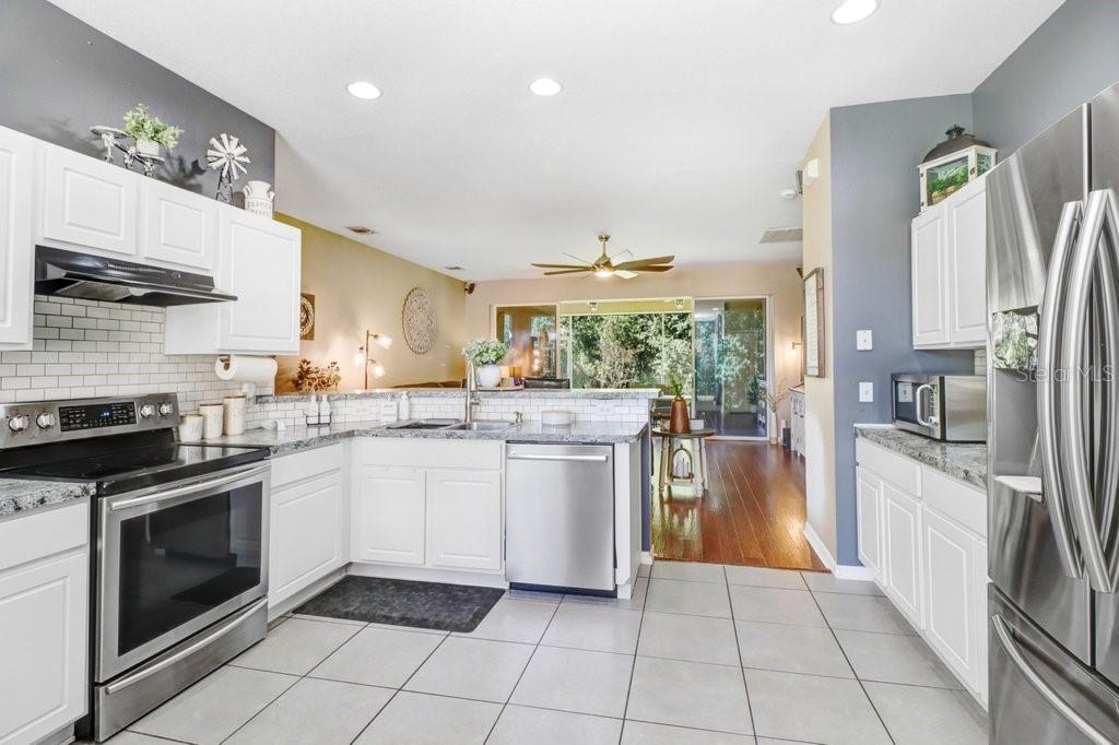 Adorable kitchen with granite countertops,stainless appliances, and beautiful backsplasn