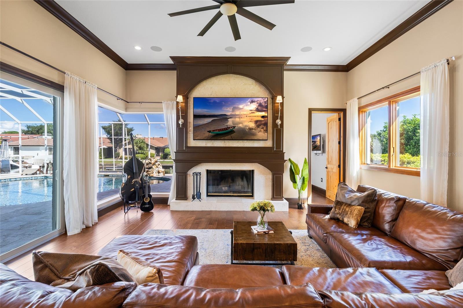 Family room with sliders to pool area, mitered glass window, and wood burning fireplace