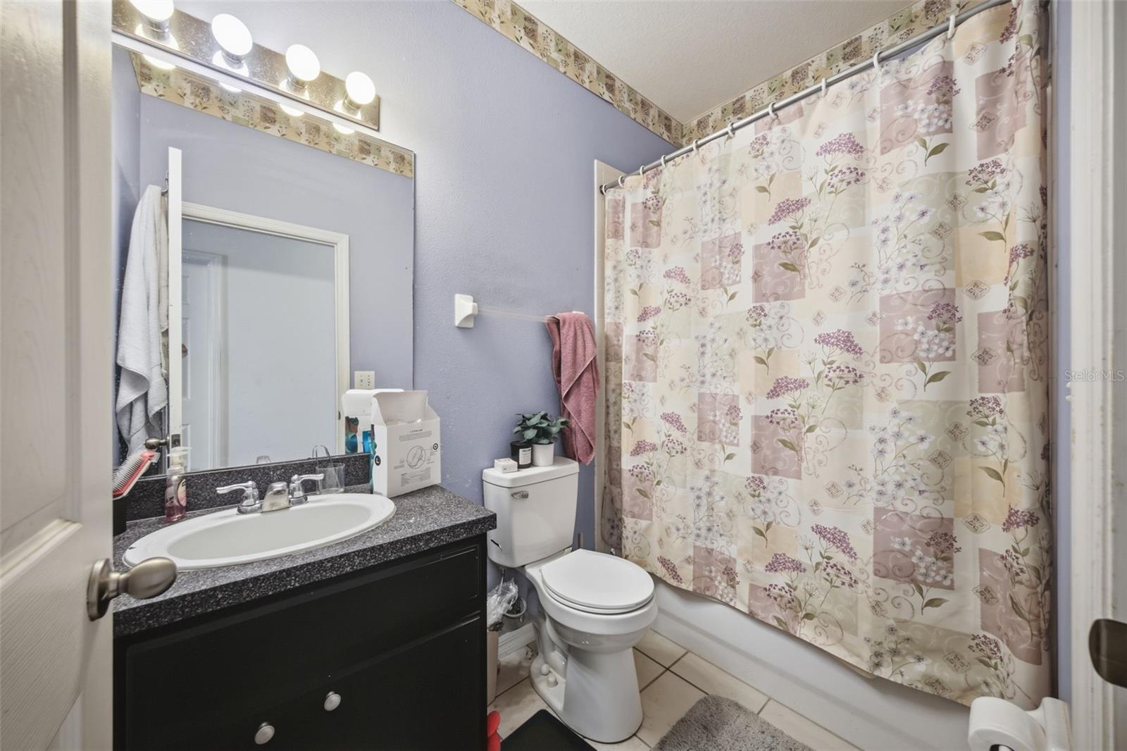 Hall bath with single vanity, tub/shower combo and tile floor
