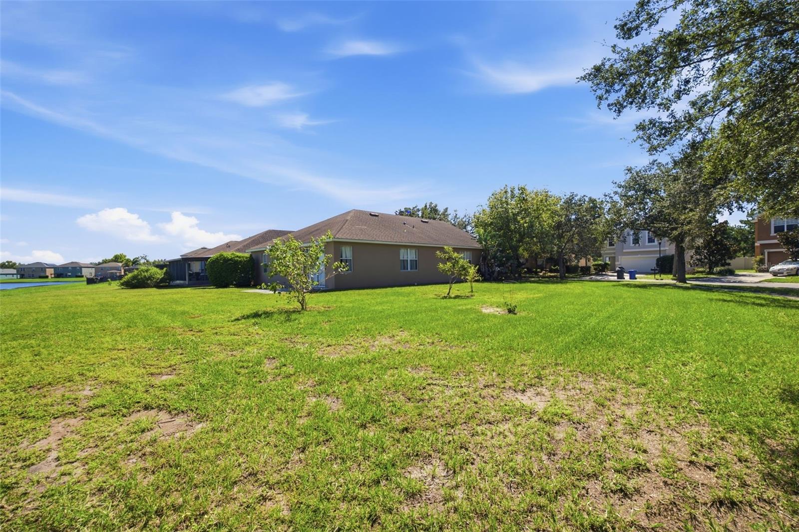 Wide lawn along side of home with pond in the distance