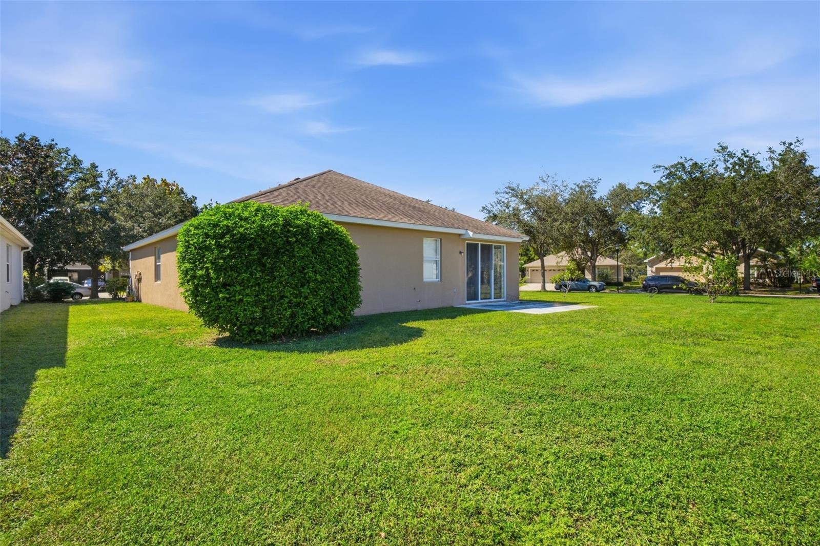 Rear of home with sliding glass doors, patio and open lawn