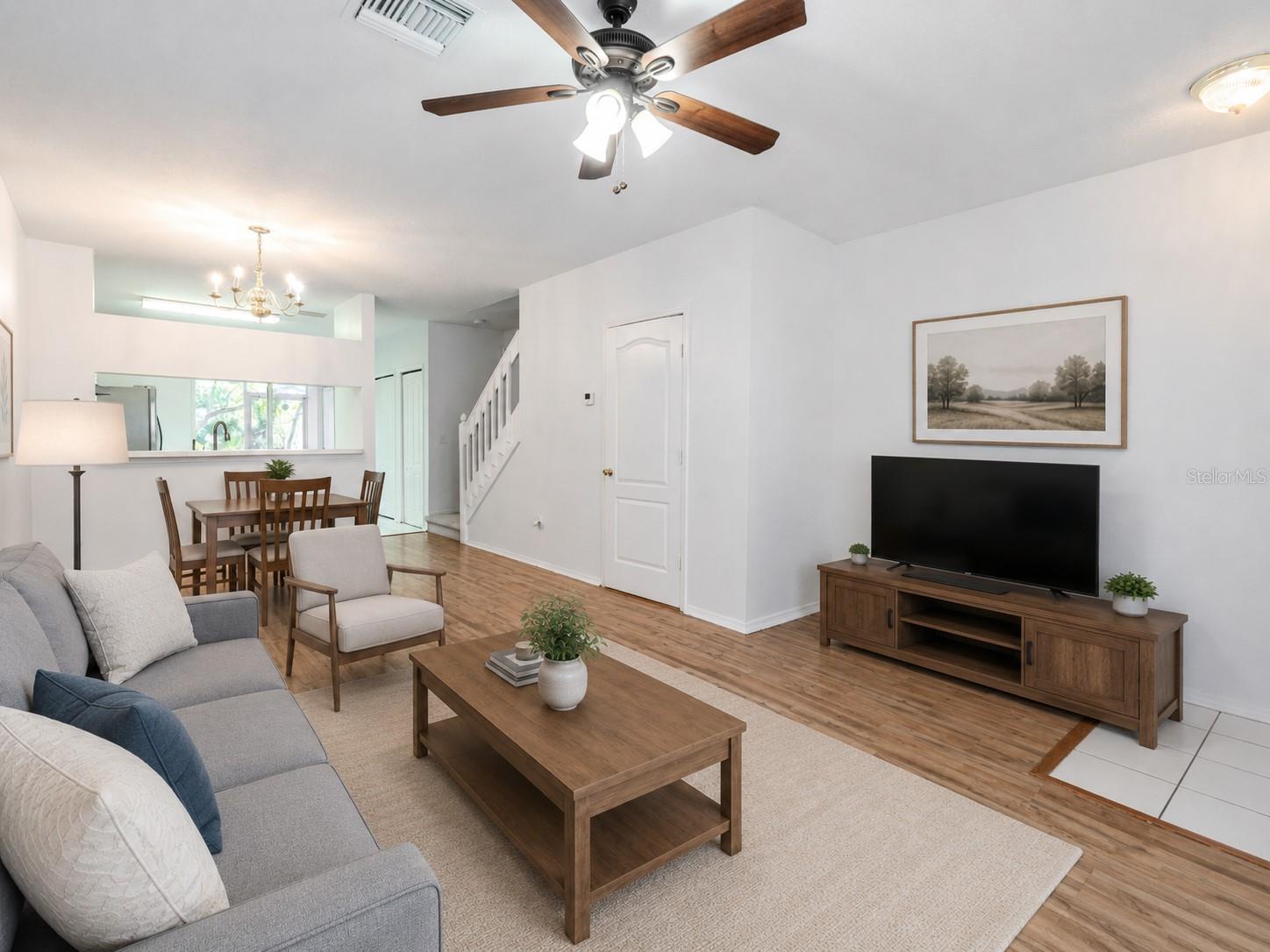 The Living room features neutral tones, wood laminate flooring, a ceiling fan with light kit and picture window. The Living room features neutral tones, wood laminate flooring, a ceiling fan with light kit and picture window.