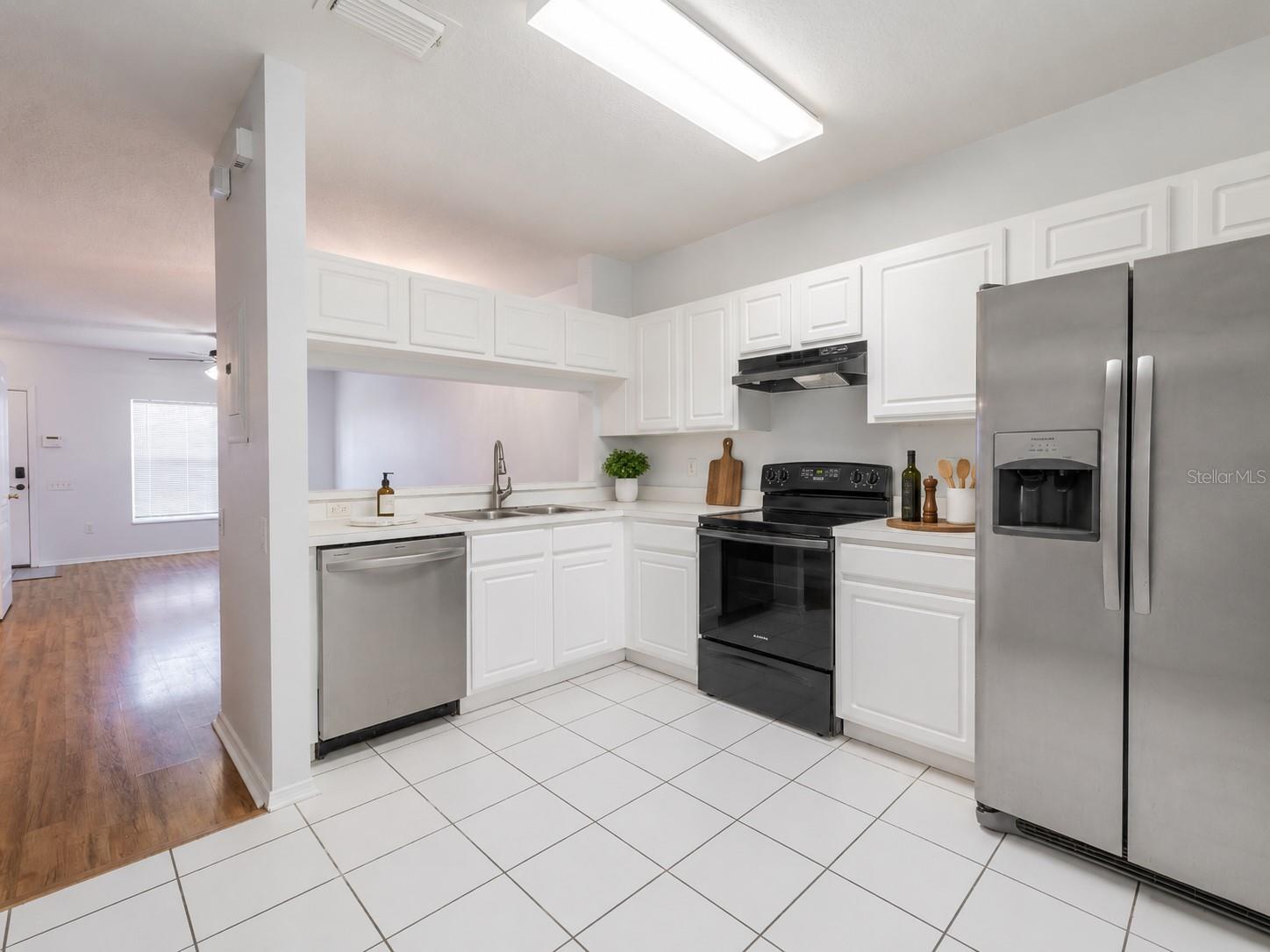 Kitchen features ceramic tile flooring, stainless steel appliances including a French door refrigerator with ice maker and water dispenser, an electric range and sliding glass door to the private screened in patio.