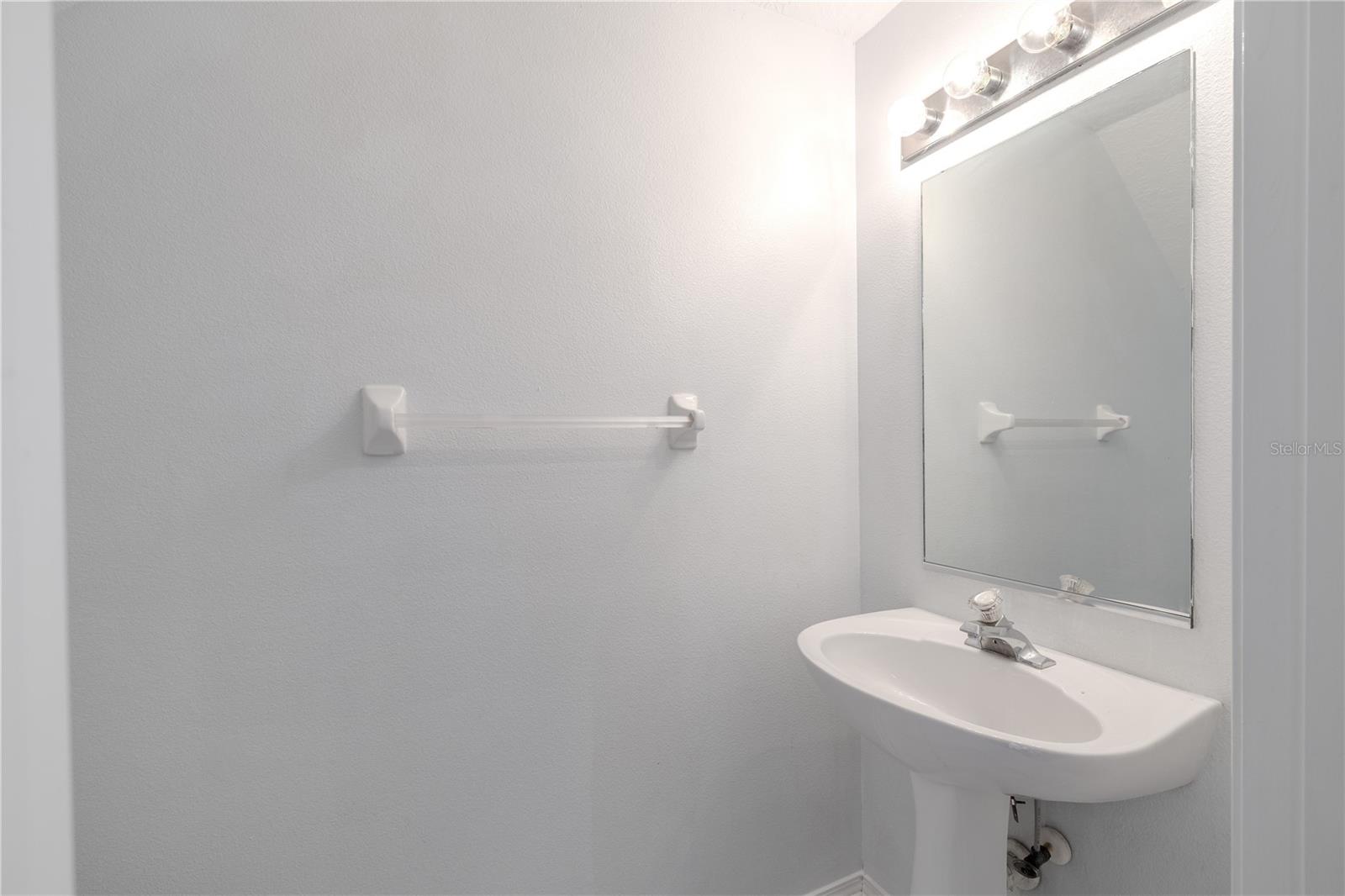 1st floor half bath off of the living room with pedestal sink and commode.