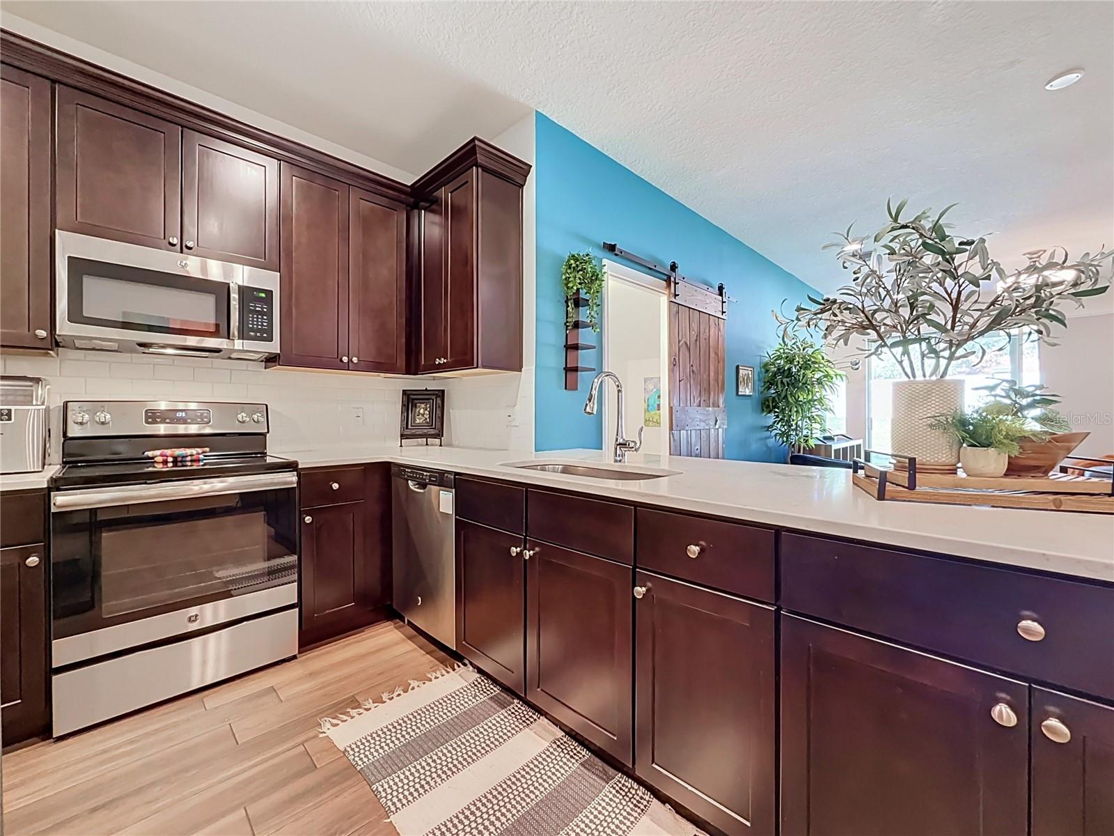 The well-appointed kitchen offers SOLID WOOD CABINETRY, GRANITE countertops, stainless steel appliances, a breakfast bar, and ample storage.