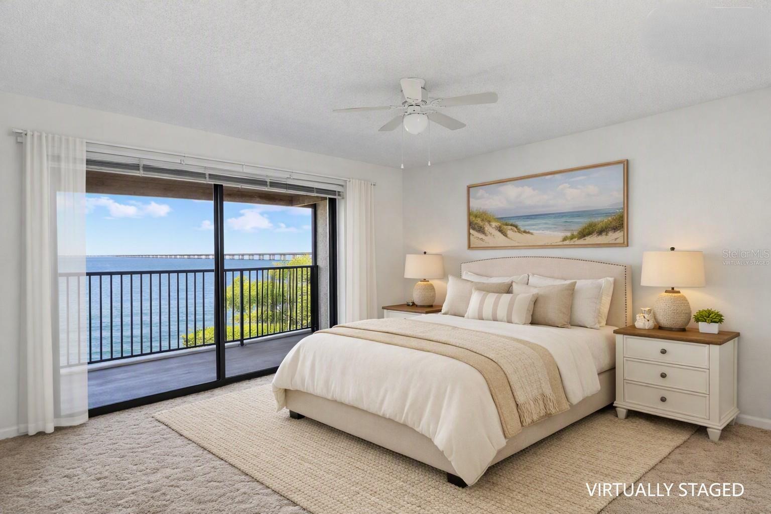 Virtually staged - primary bedroom over looking the balcony with full panoramic water views