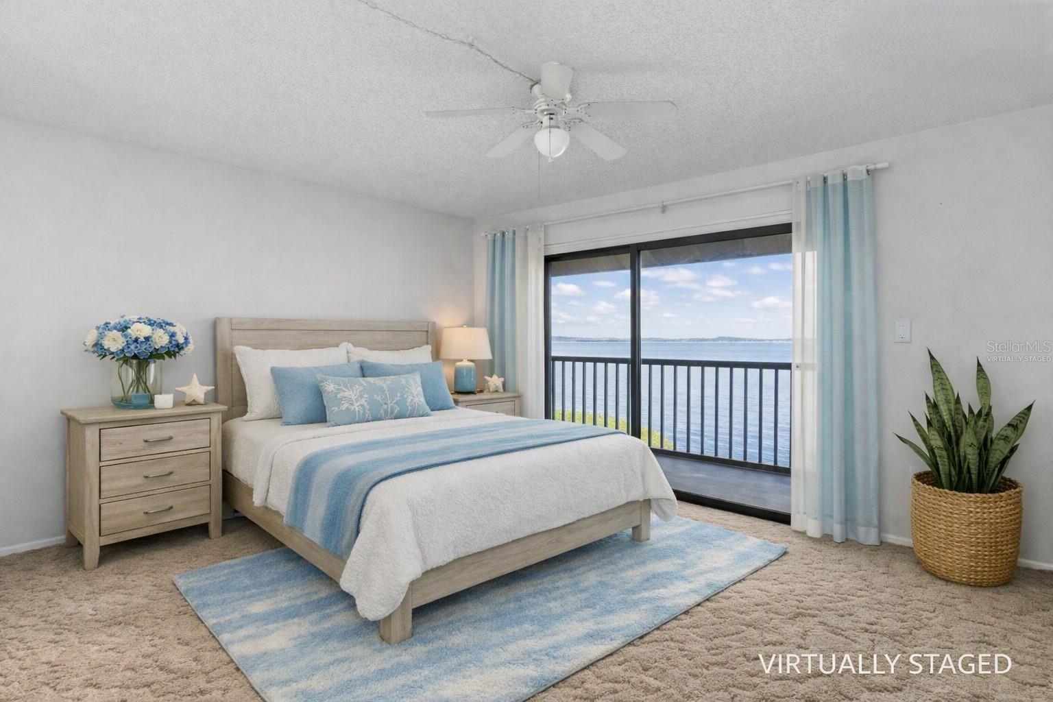 Virtually staged primary bedroom looking towards the balcony and fully panoramic water views.