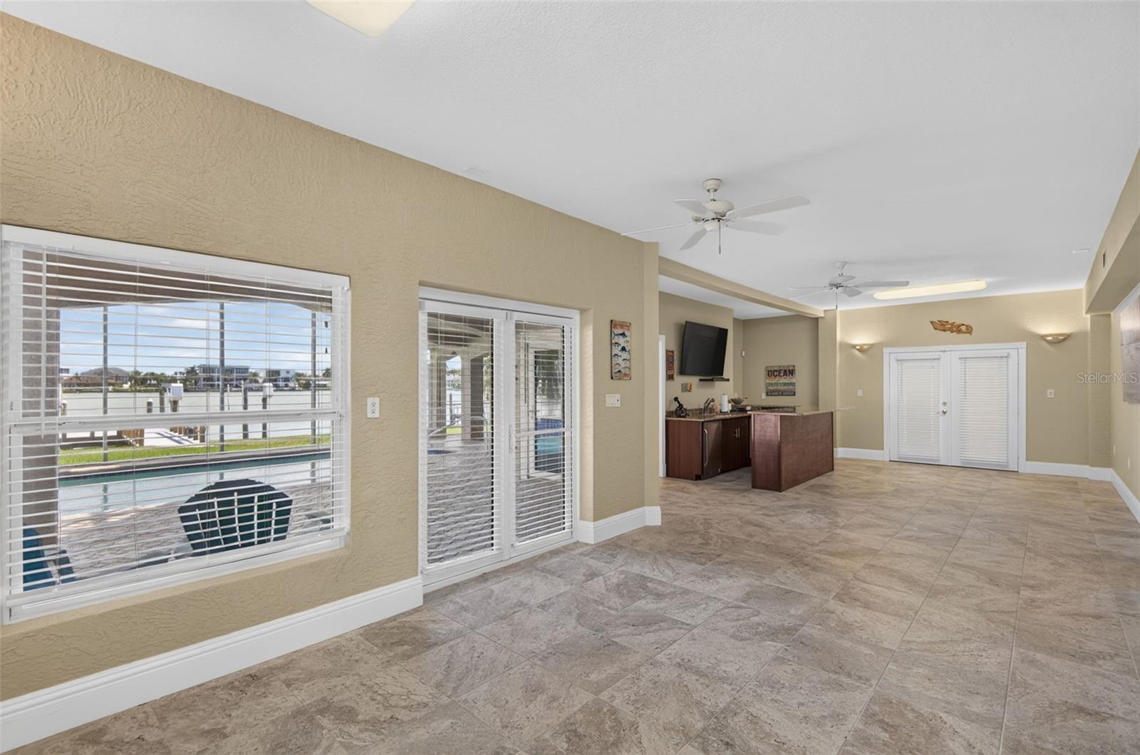 BONUS AREA DOWNSTAIRS BETWEEN GARAGES DOORS TO WEST GARAGE & POOL PATIO