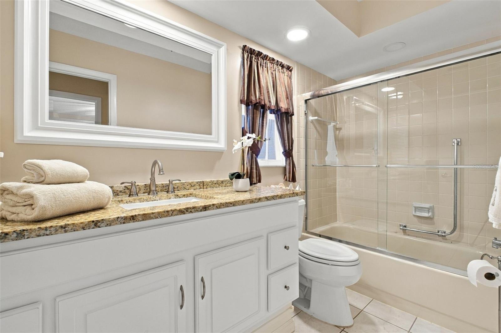 Beautifully updated hall bath with newer oversized vanity with stone top, mirror, recessed lighting, and tub/shower combo~