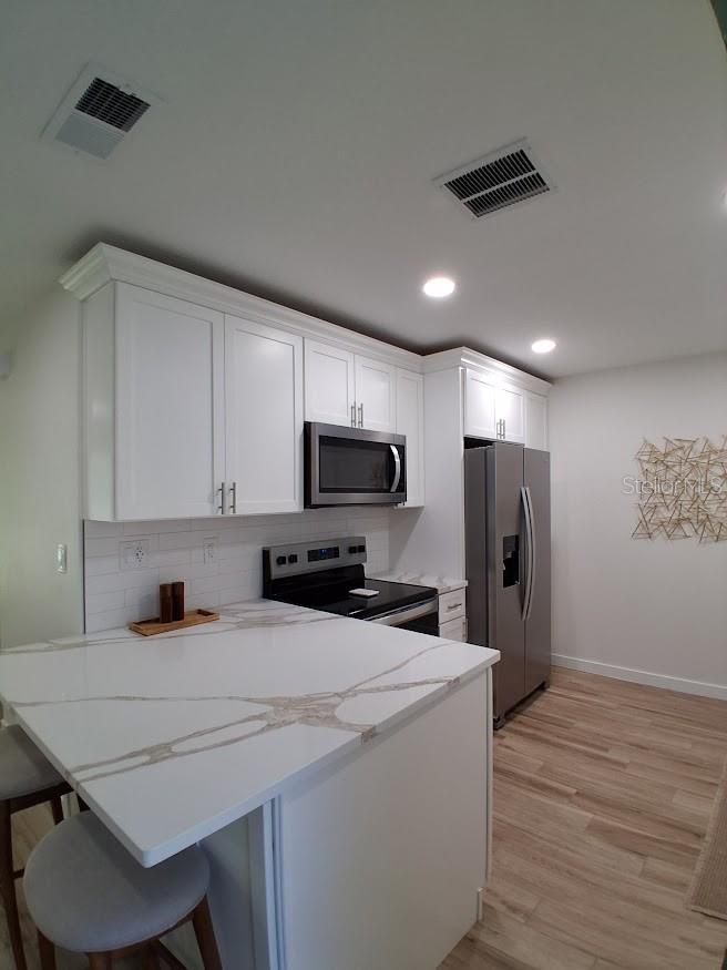 Kitchen, west side (refrigerator, microwave, stove and serving island).