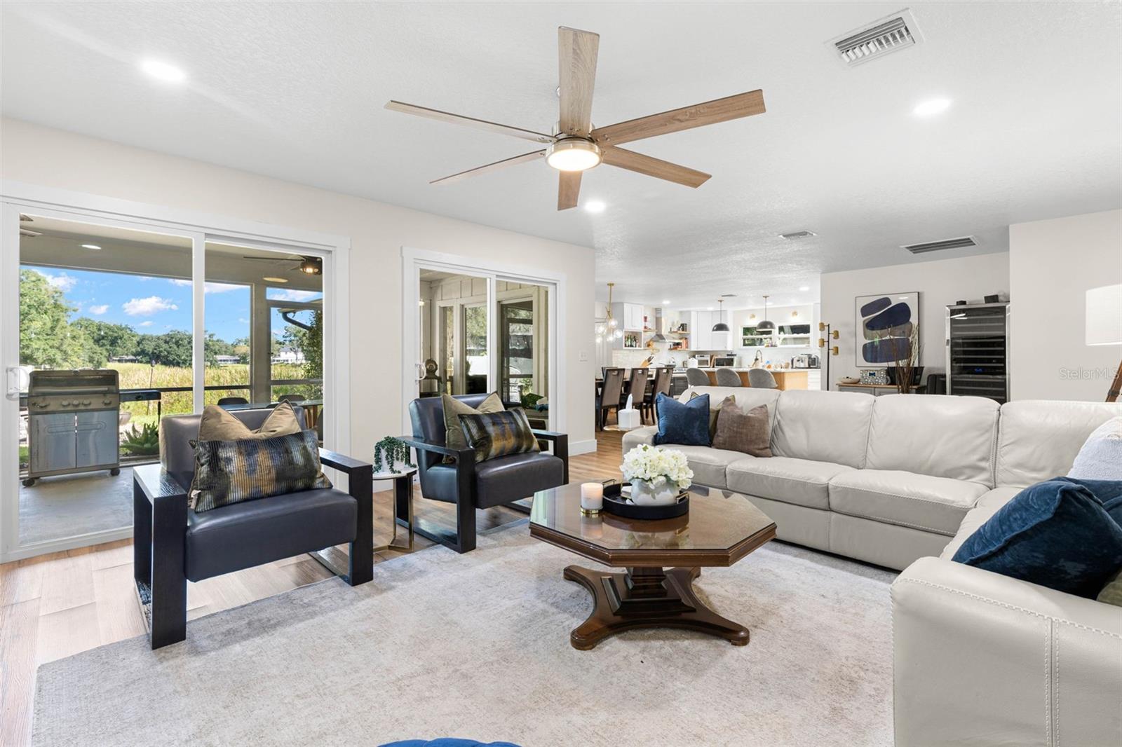 Natural light pours into the living room through sliding glass doors overlooking the backyard, while the open floor plan provides an easy connection to the dining area and kitchen. Step outside to the screened porch for an effortless extension of your indoor living space.