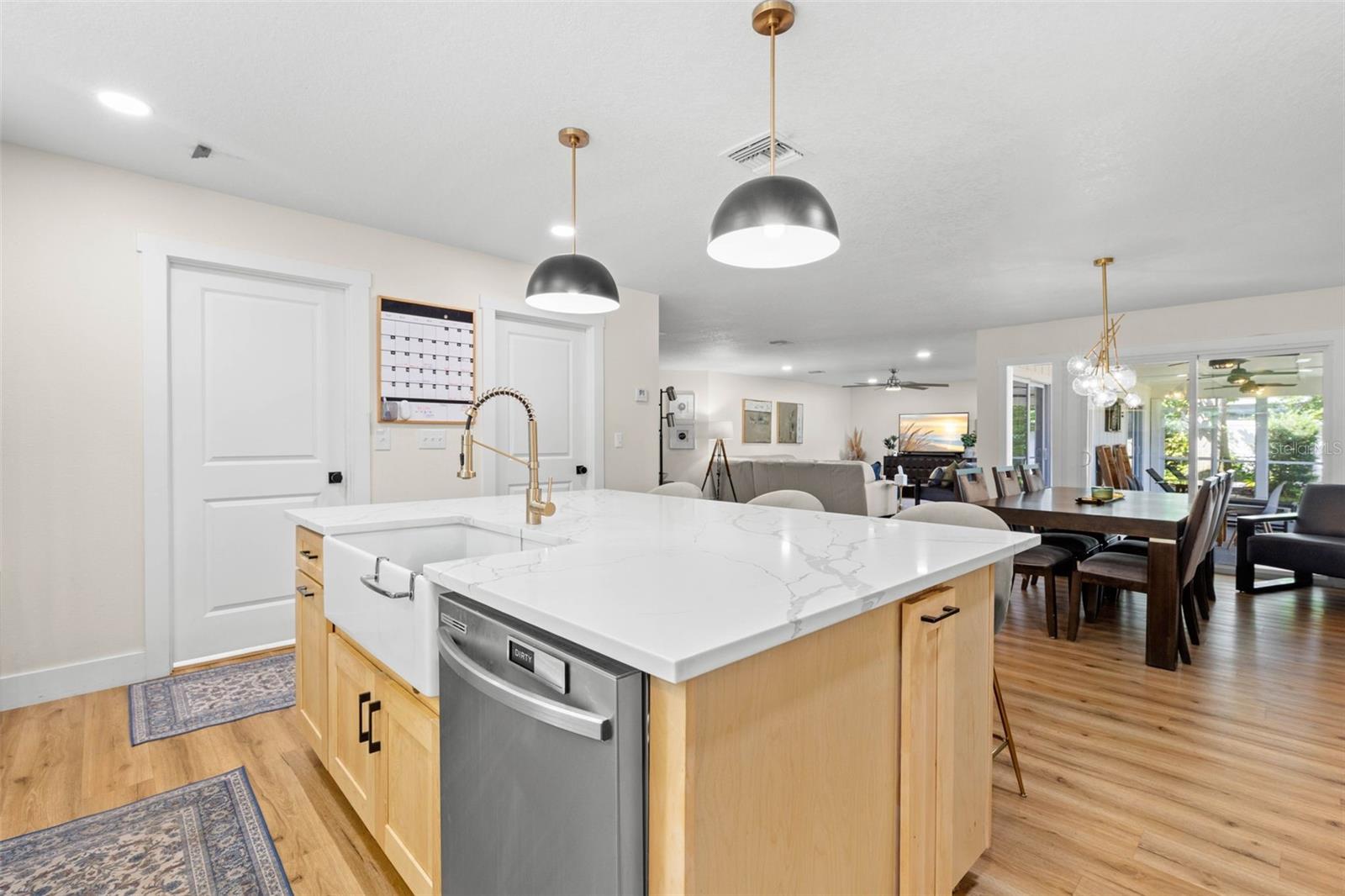 Designed with entertaining in mind, the impressive center island features a farmhouse-style apron-front sink, built-in dishwasher, ample workspace, and additional storage. The open layout keeps the kitchen connected to the dining and living areas, making everyday gatherings effortless.
