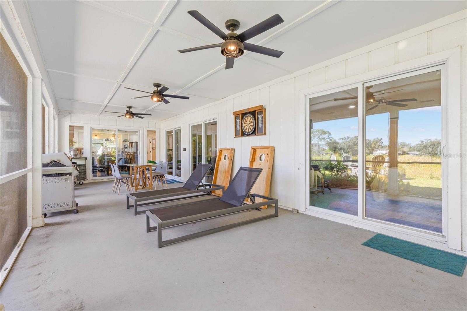 An impressive screened porch extends across the back of the home, offering plenty of room for outdoor dining, lounging, and entertaining. Three ceiling fans provide added comfort, while multiple sliding glass doors connect this versatile retreat to the interior living spaces.