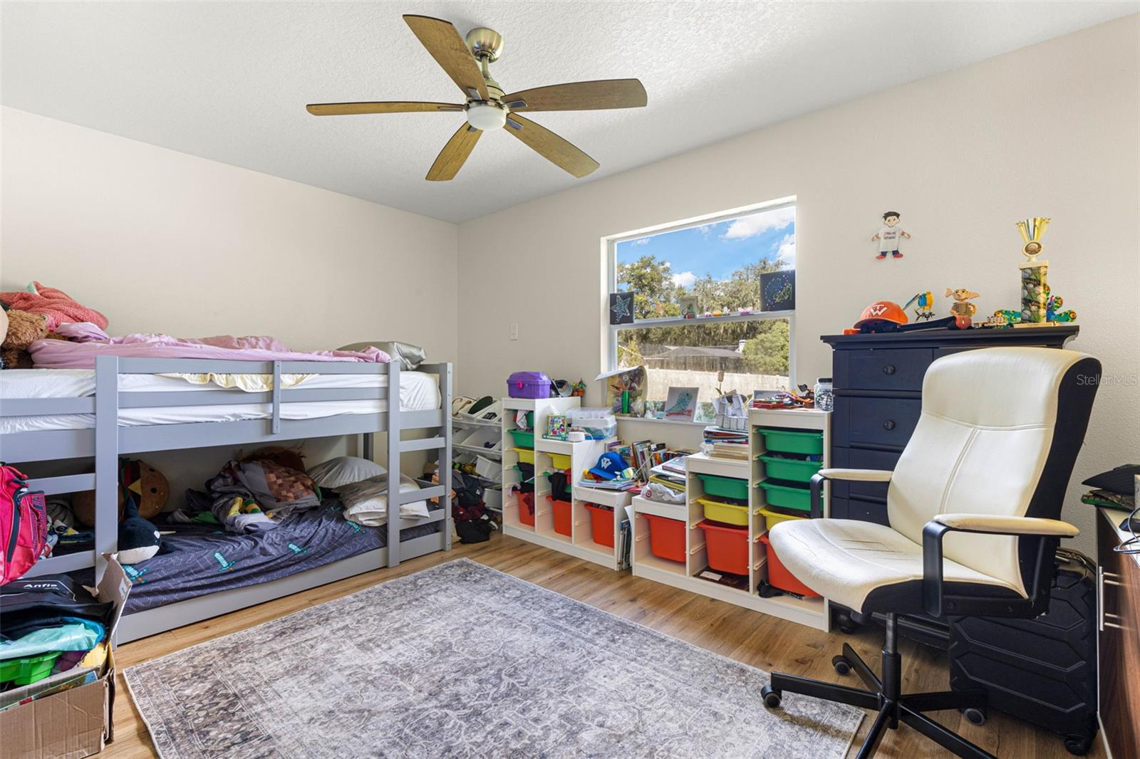 Bedroom two offers a comfortable layout with wood-look luxury vinyl flooring, a contemporary ceiling fan, and a large window that welcomes natural light. Easily adaptable as a guest bedroom, home office, or creative space to suit your needs.