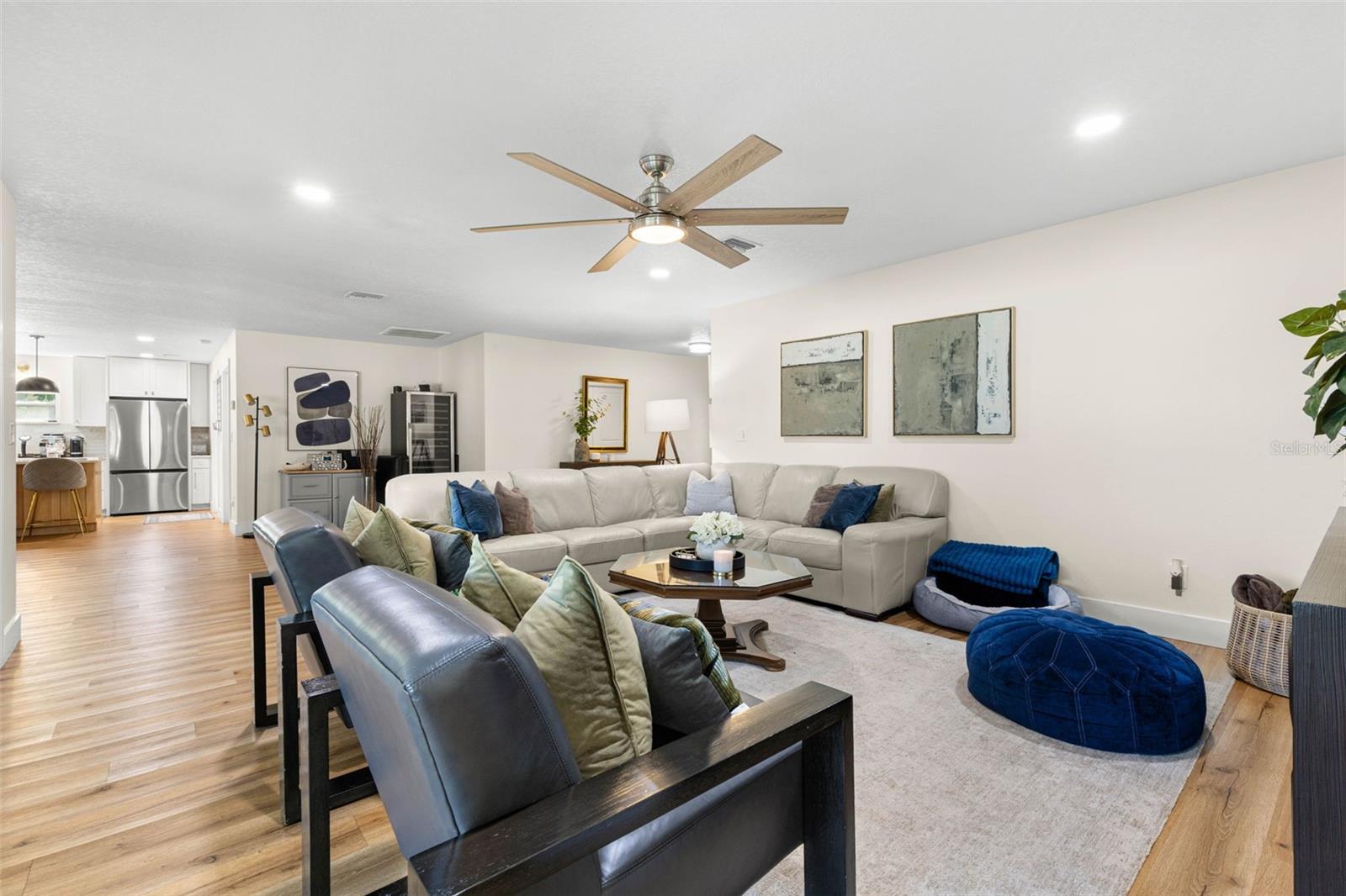 The open-concept floor plan creates an effortless flow between the generously proportioned living room and kitchen. Continuous wood-look luxury vinyl flooring, neutral finishes, and recessed lighting bring warmth and continuity to the main living areas.