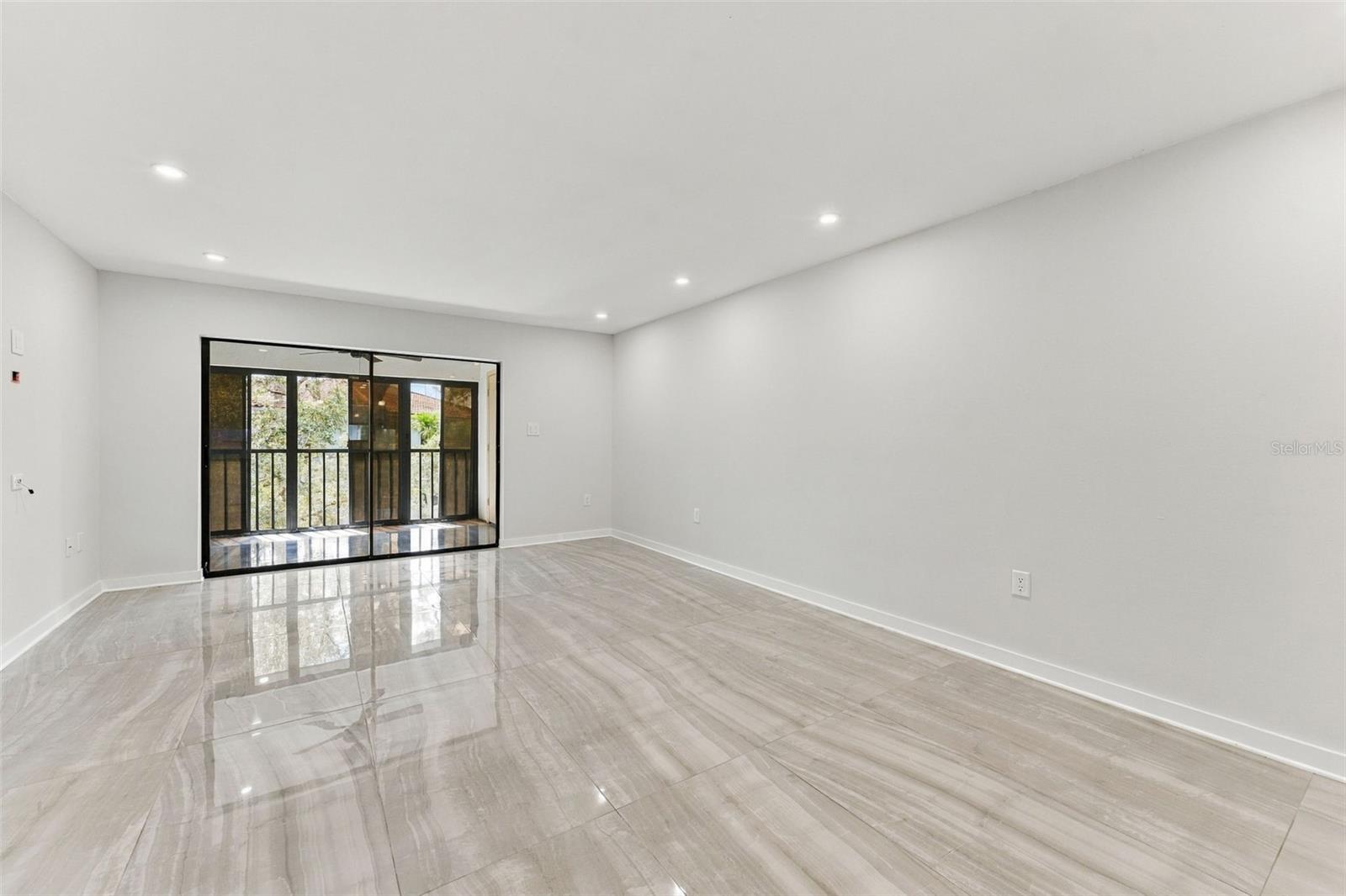 Living room with new tile flooring and sliding glass doors leading to the back patio