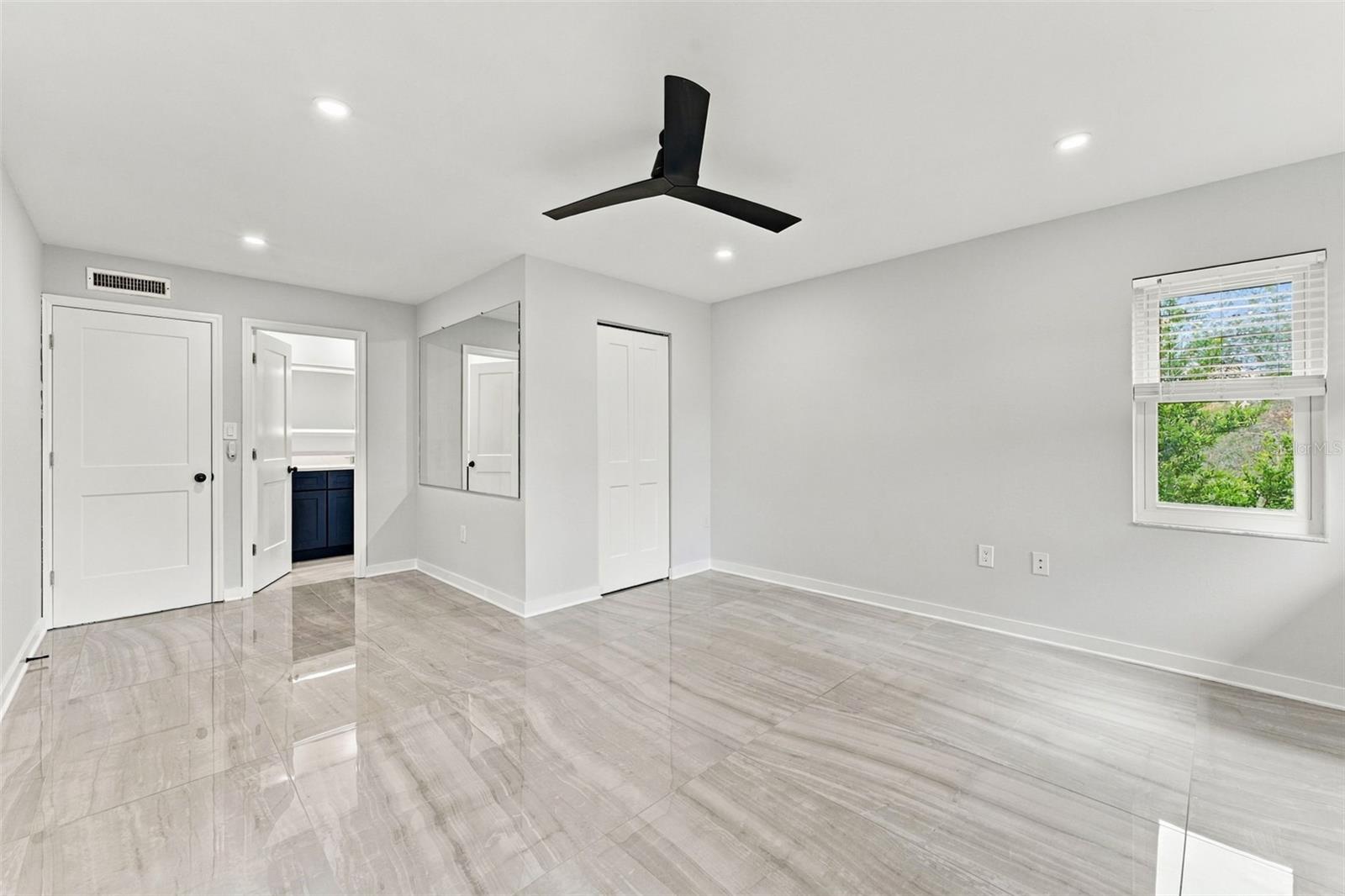 Generously sized primary bedroom with new flooring, lighting and ceiling fan