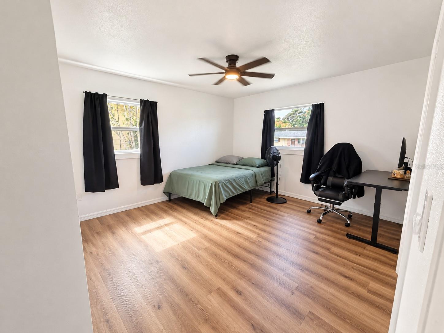 Flexible bedroom space with wood-look flooring, neutral finishes, and natural light with built in closet